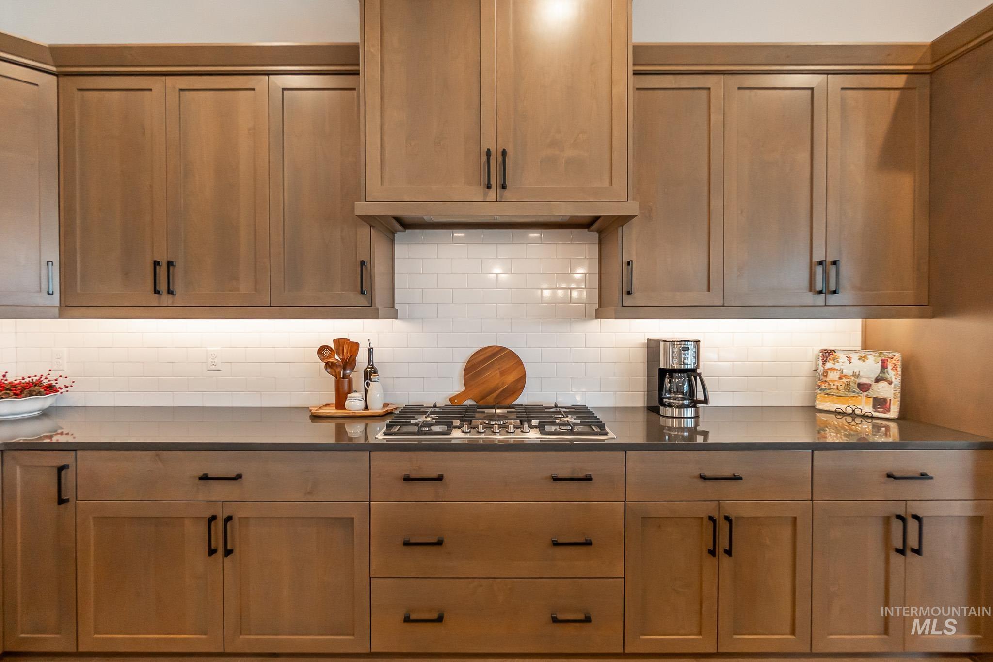 Kitchen featuring dark countertops, stainless steel gas stovetop, and backsplash