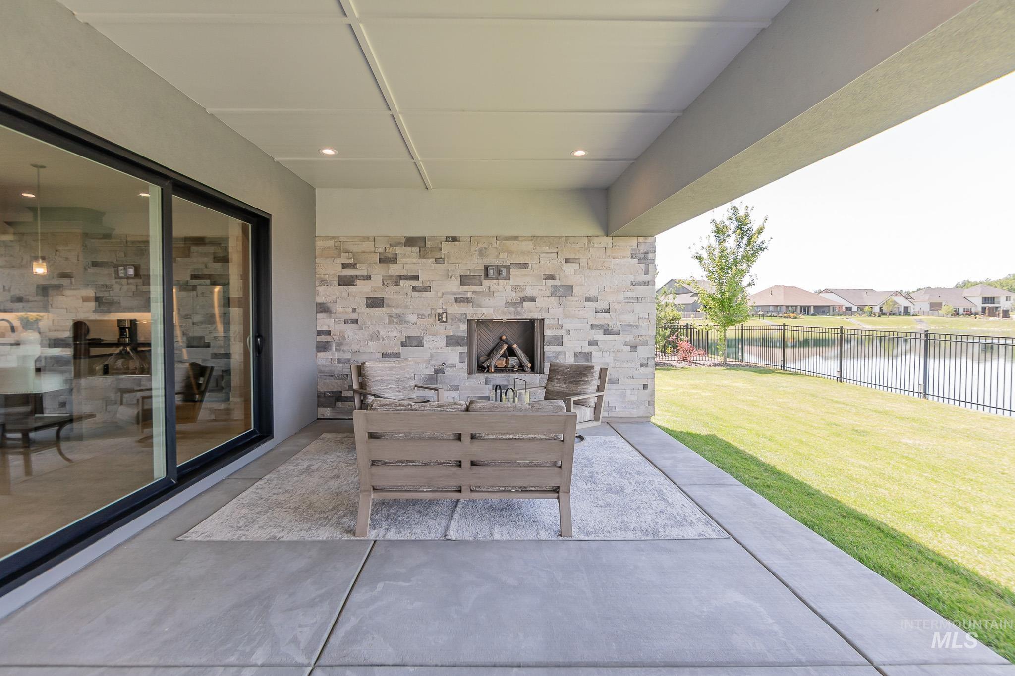 View of patio / terrace with exterior fireplace, a water view, and a residential view