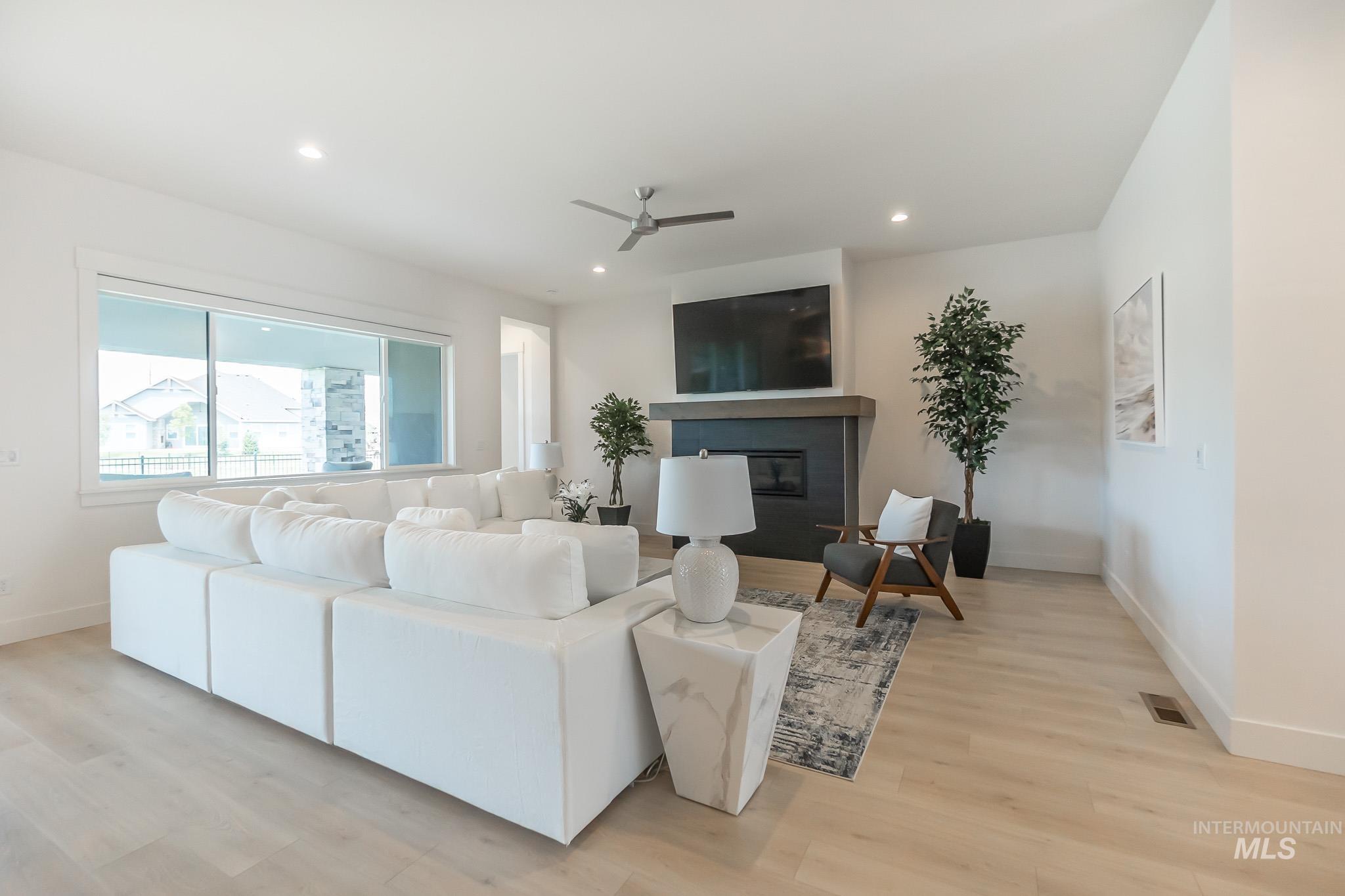 Living area featuring a glass covered fireplace, recessed lighting, light wood-type flooring, and a ceiling fan