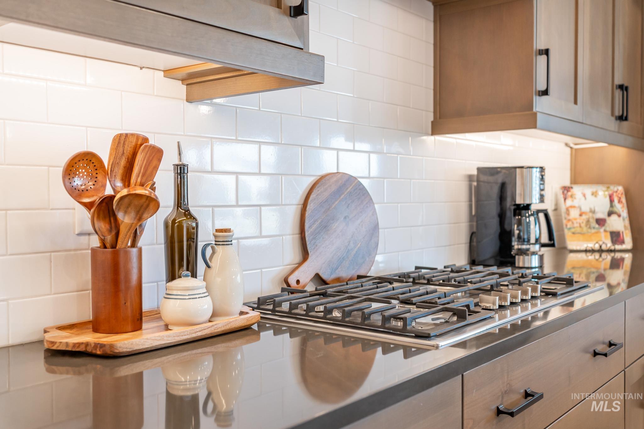 Kitchen view of stainless steel gas cooktop and decorative backsplash