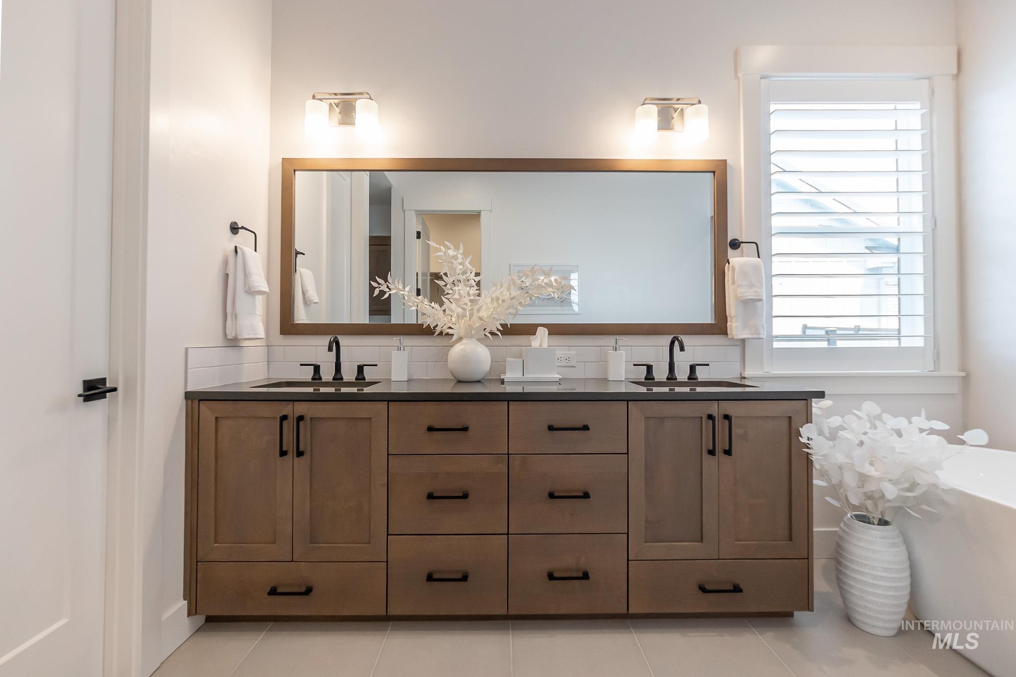 Full bathroom with double vanity, a freestanding bath, and tile patterned flooring
