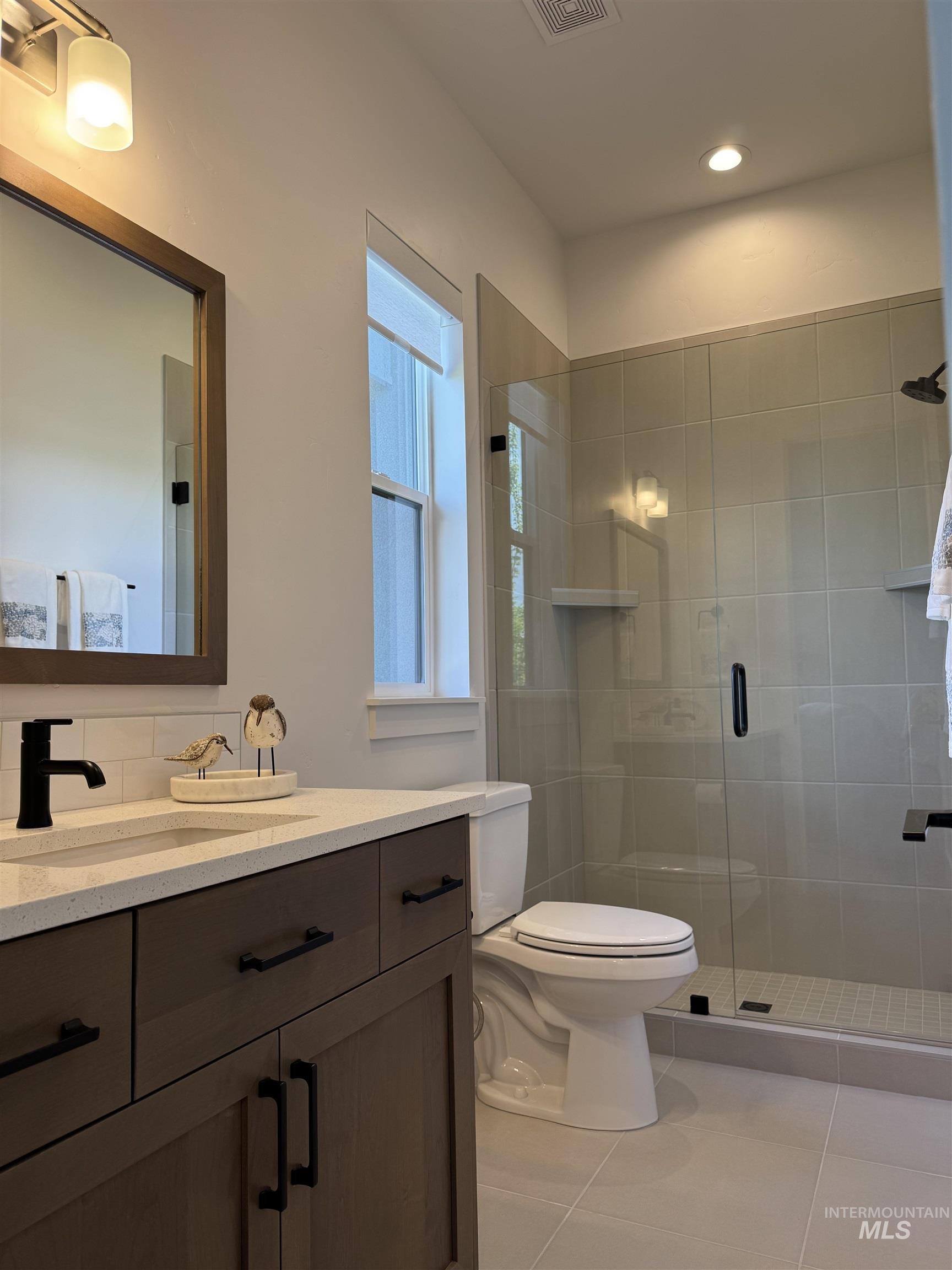 Bathroom with vanity, a stall shower, tile patterned floors, and recessed lighting