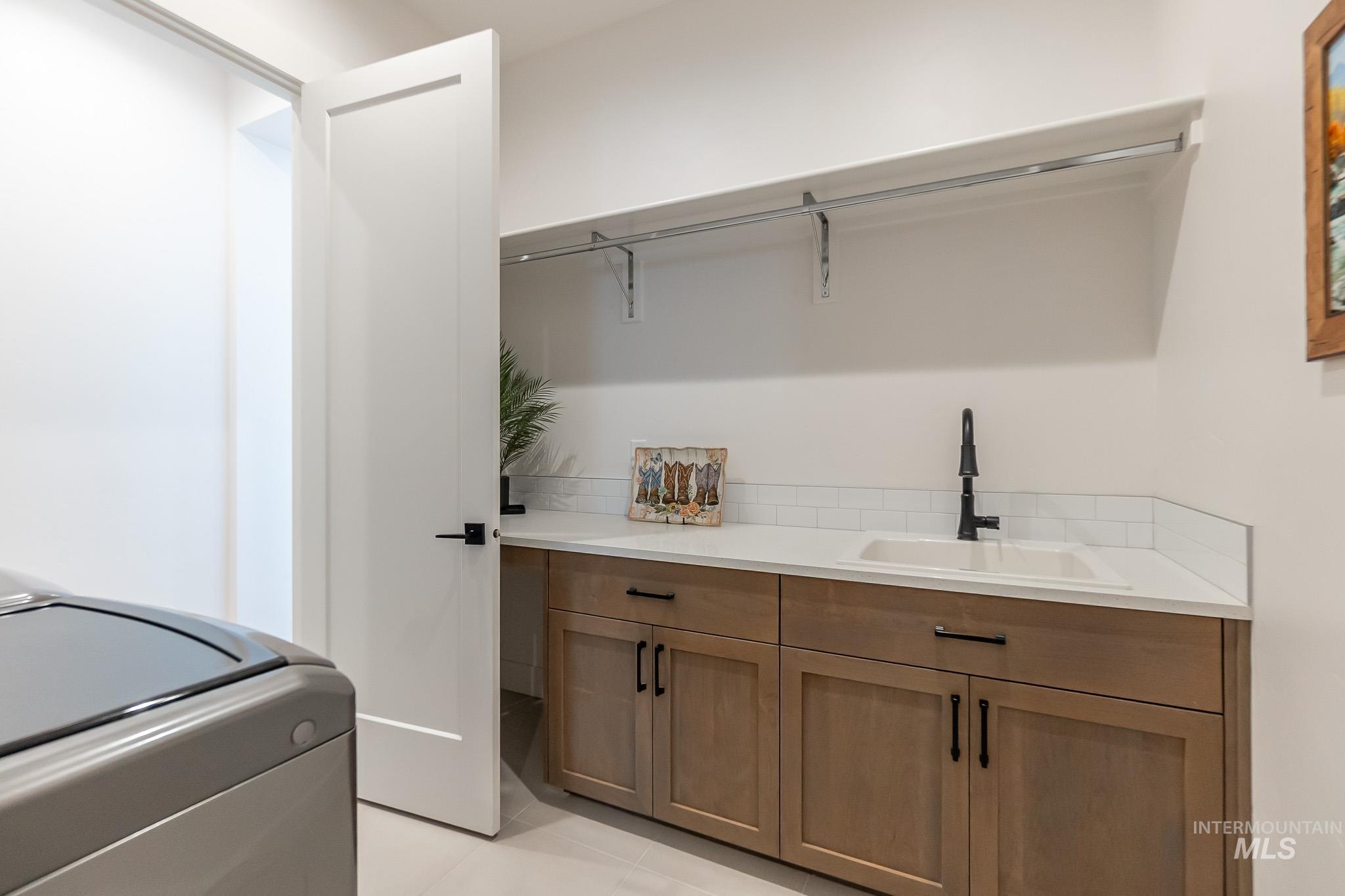 Washroom with washer / dryer and light tile patterned flooring