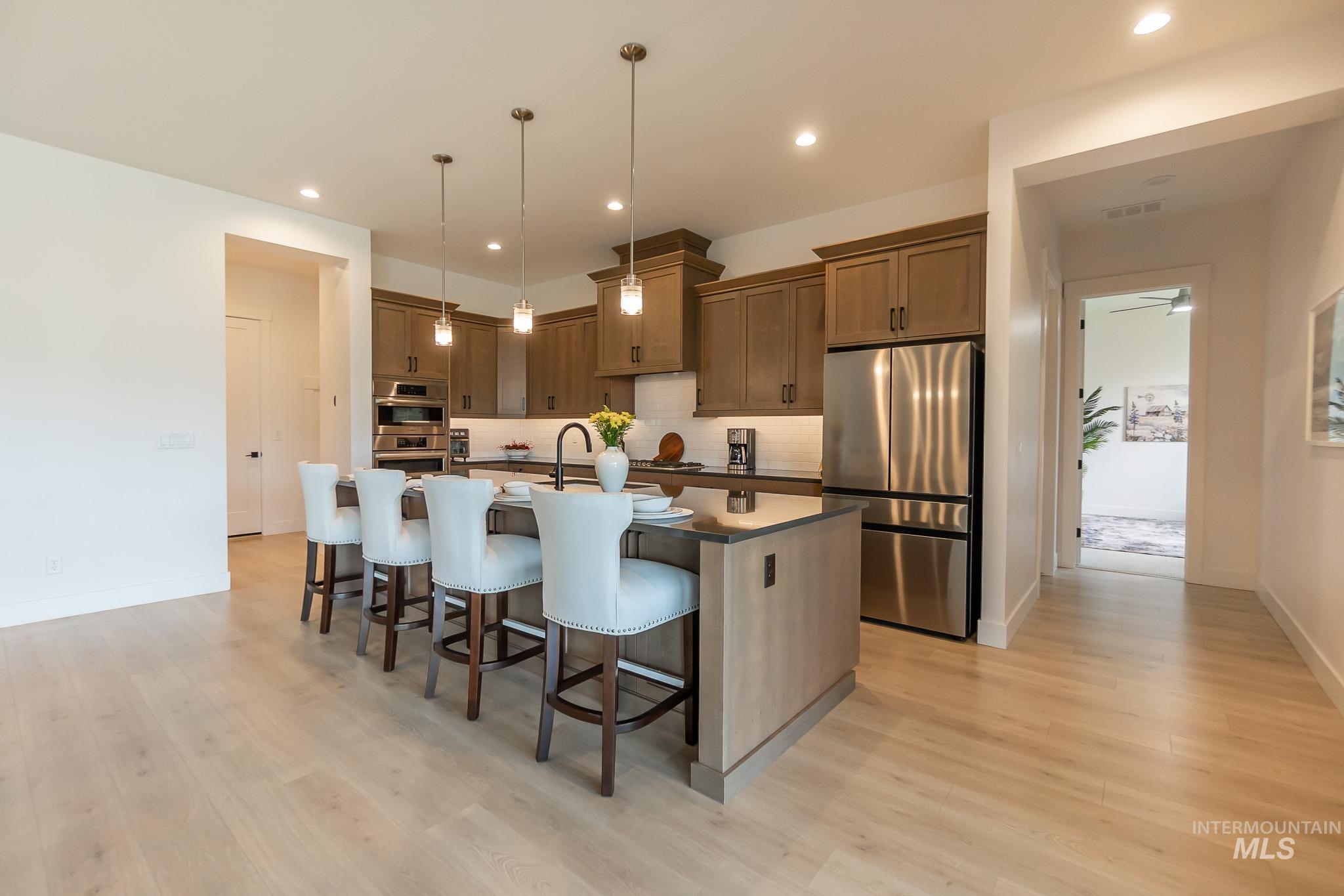 Kitchen featuring stainless steel appliances, a kitchen breakfast bar, light wood-style floors, a kitchen island with sink, and recessed lighting