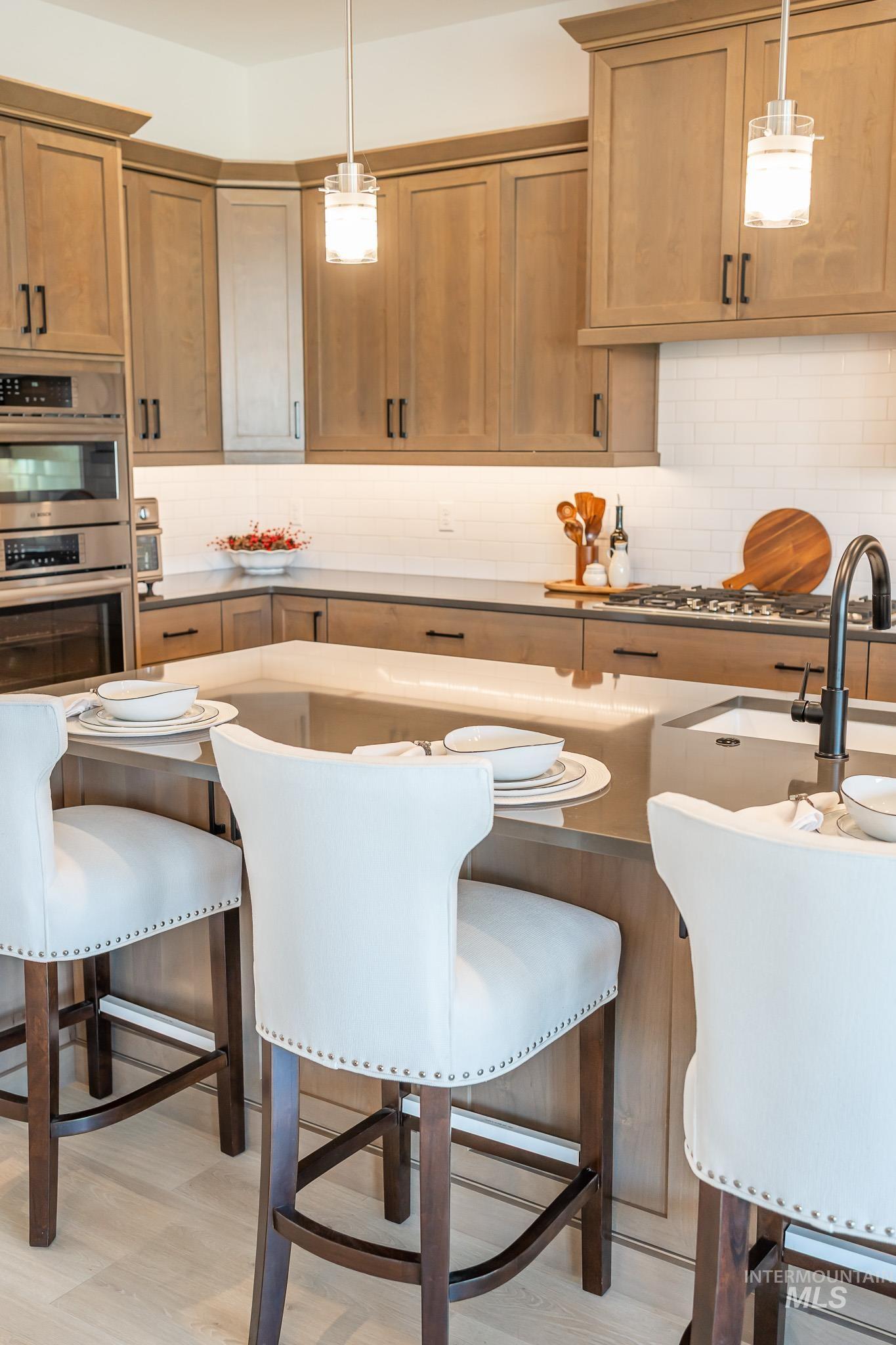 Kitchen with stainless steel appliances, a kitchen breakfast bar, backsplash, and decorative light fixtures