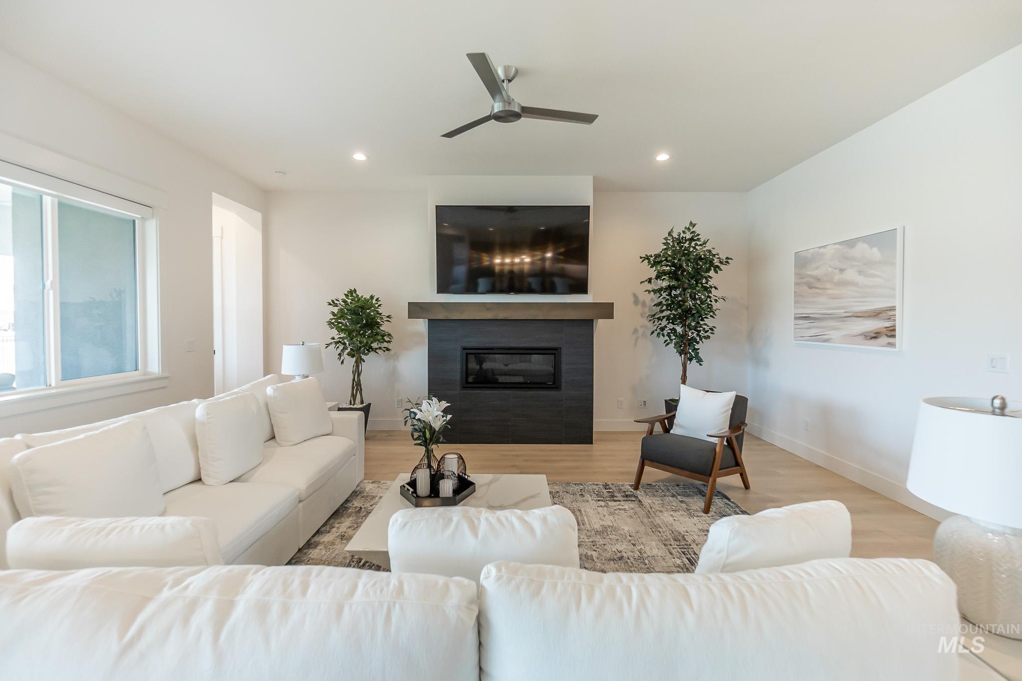 Living area with a glass covered fireplace, recessed lighting, a ceiling fan, and wood finished floors