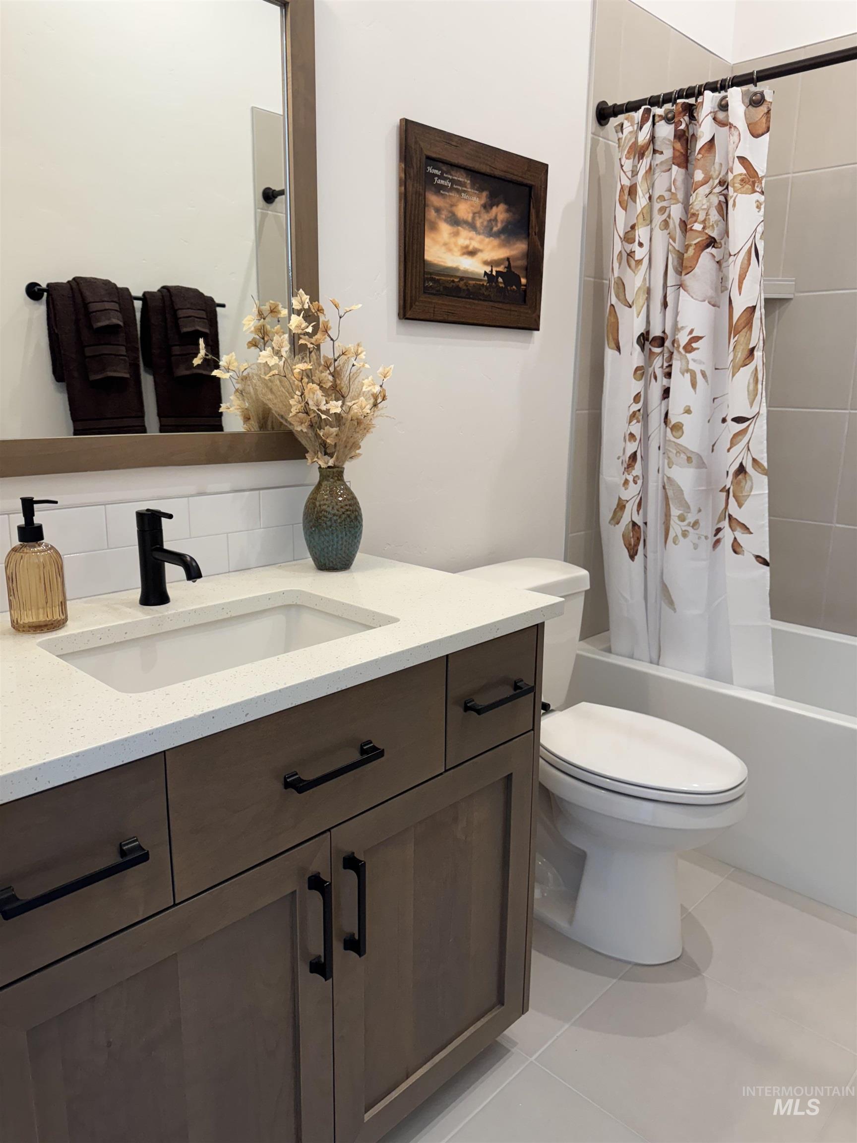 Bathroom with vanity, shower / bathtub combination with curtain, and tile patterned floors