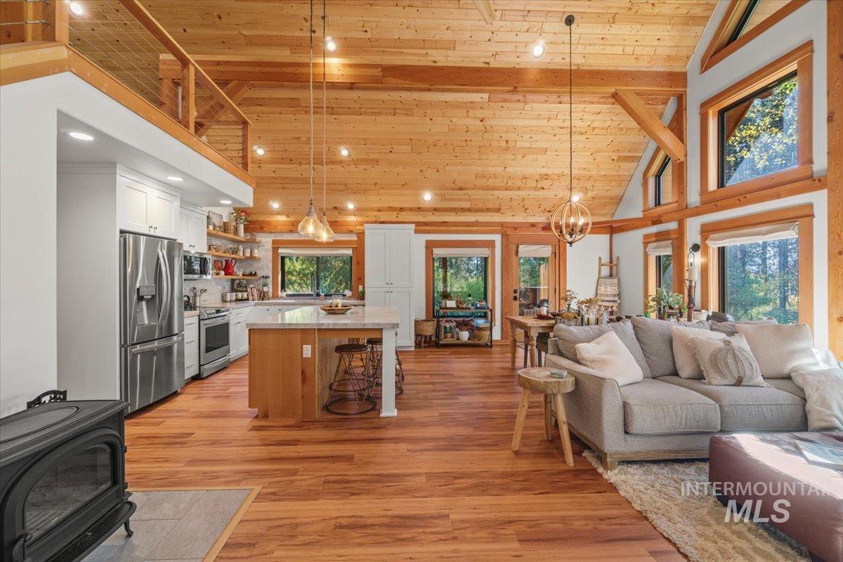 Kitchen with open shelves, high vaulted ceiling, decorative light fixtures, a wood ceiling with exposed beams, and stainless steel appliances