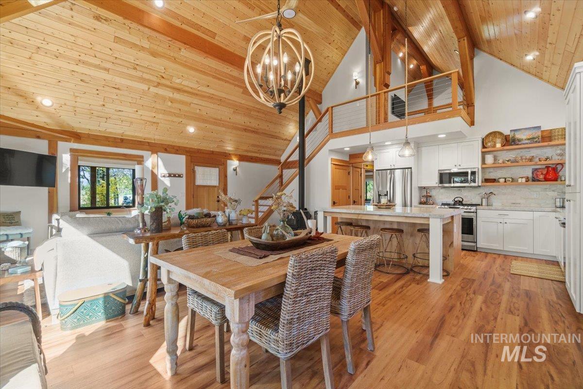 Dining area with stairs, light wood-style flooring, high vaulted ceiling, wood ceiling, and recessed lighting