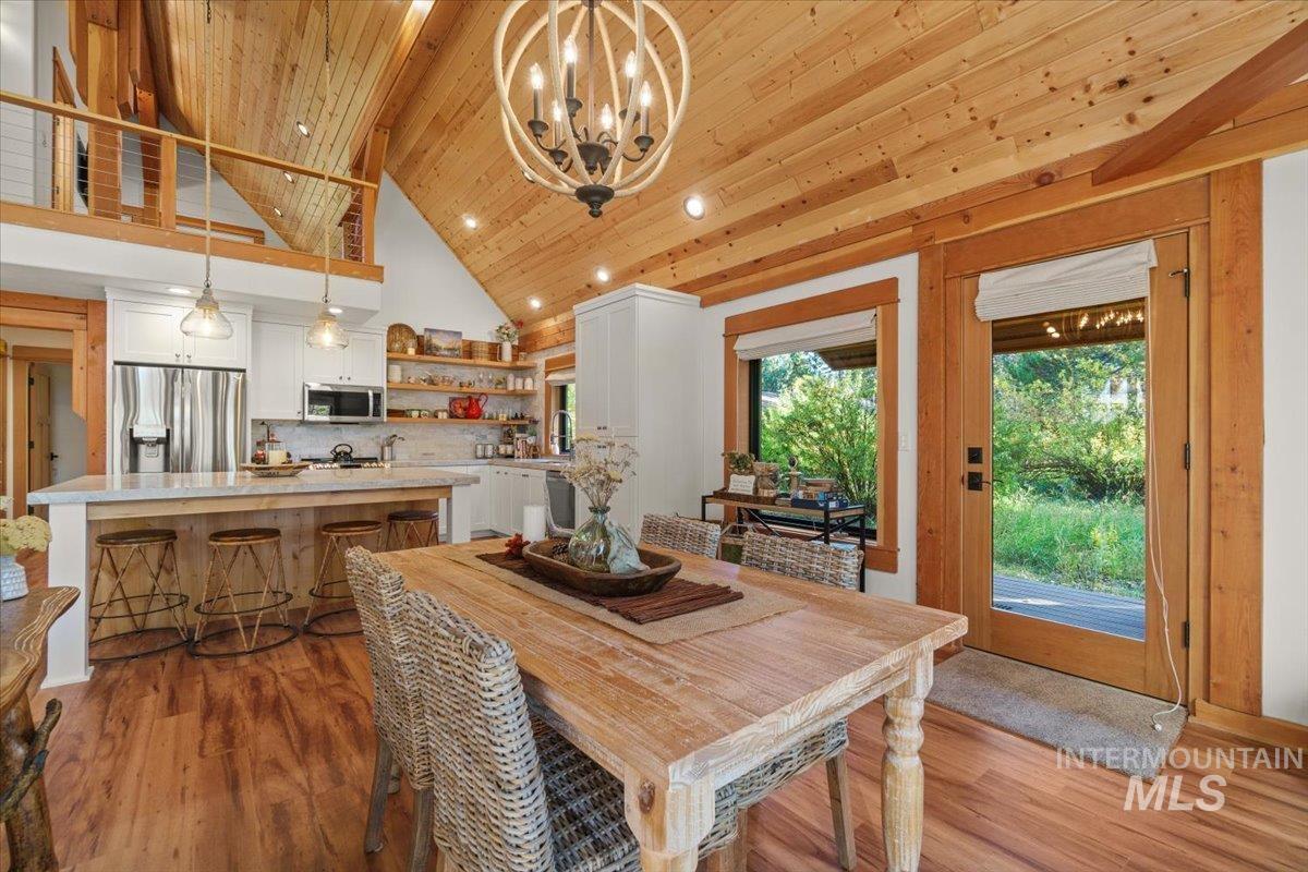Dining area featuring high vaulted ceiling, recessed lighting, dark wood-style flooring, a chandelier, and wooden ceiling