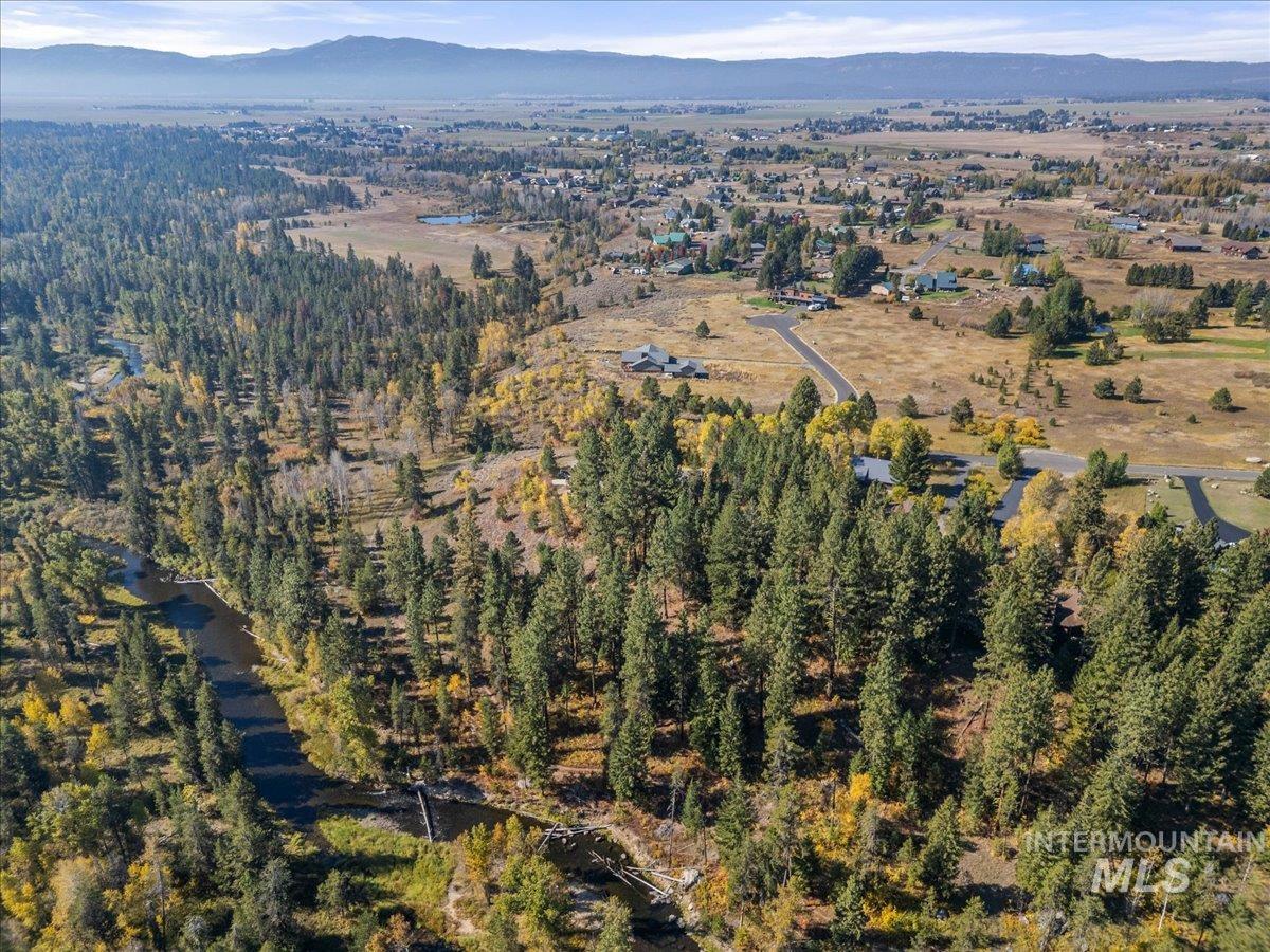 Aerial view of property and surrounding area with a mountainous background and a heavily wooded area