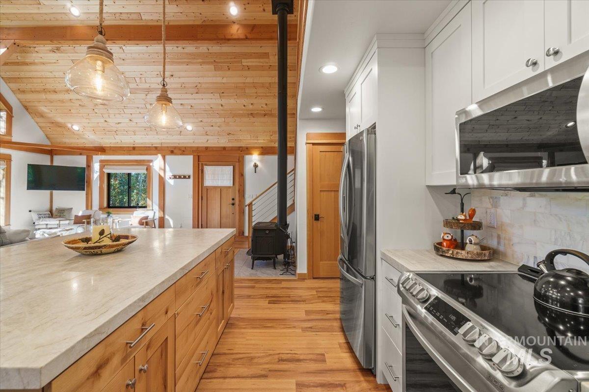 Kitchen with stainless steel appliances, open floor plan, recessed lighting, pendant lighting, and light wood-type flooring