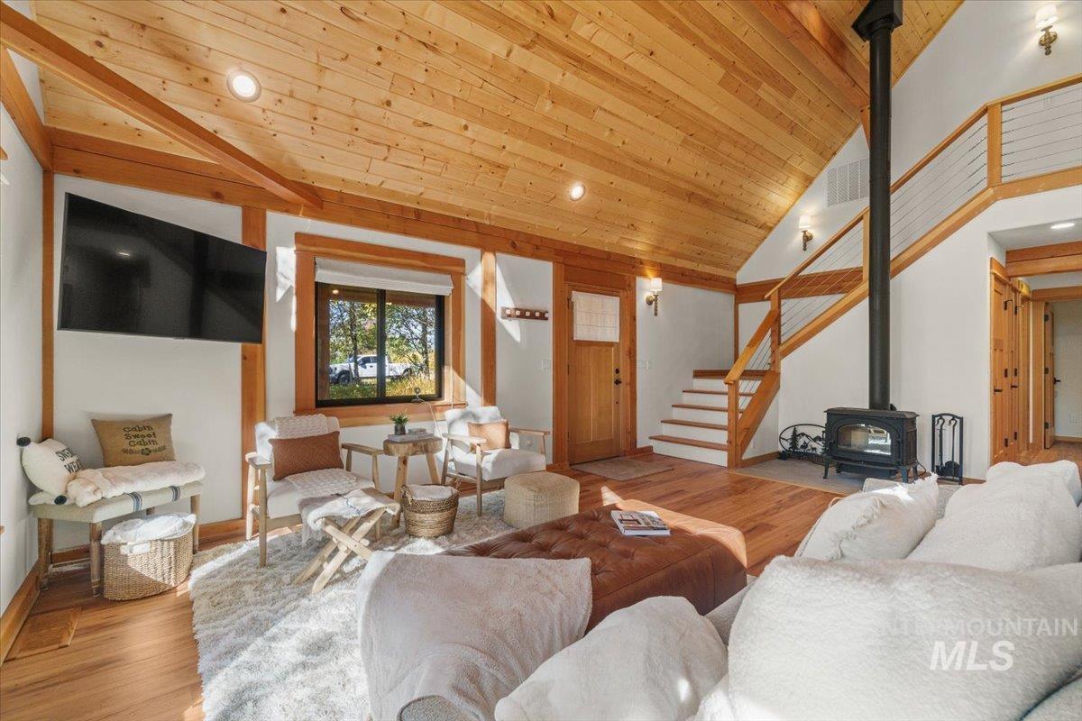 Living room featuring wood finished floors, a wood stove, stairs, wooden ceiling, and recessed lighting