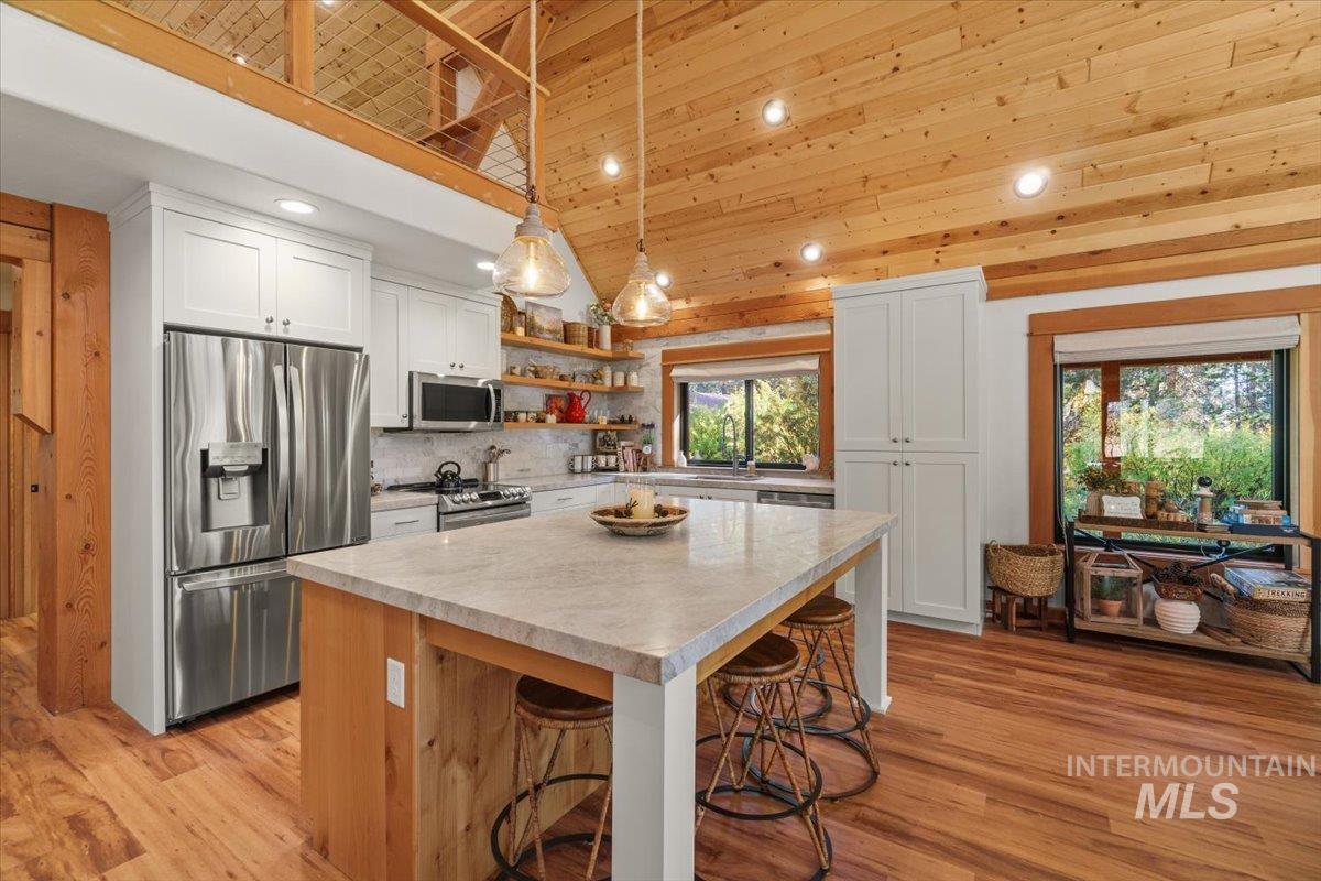 Kitchen featuring appliances with stainless steel finishes, hanging light fixtures, light wood-type flooring, white cabinetry, and recessed lighting