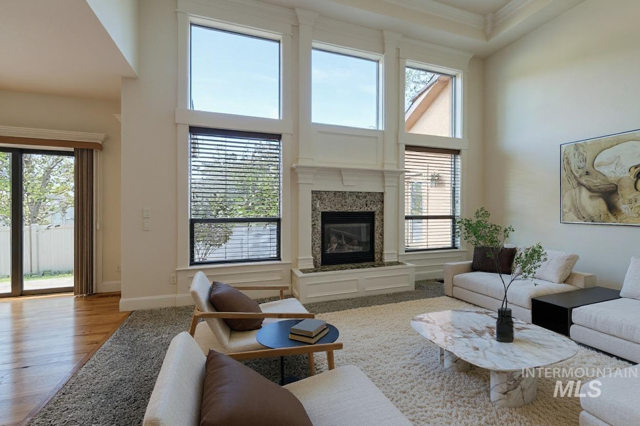 Living room featuring a high ceiling, a fireplace, and wood finished floors