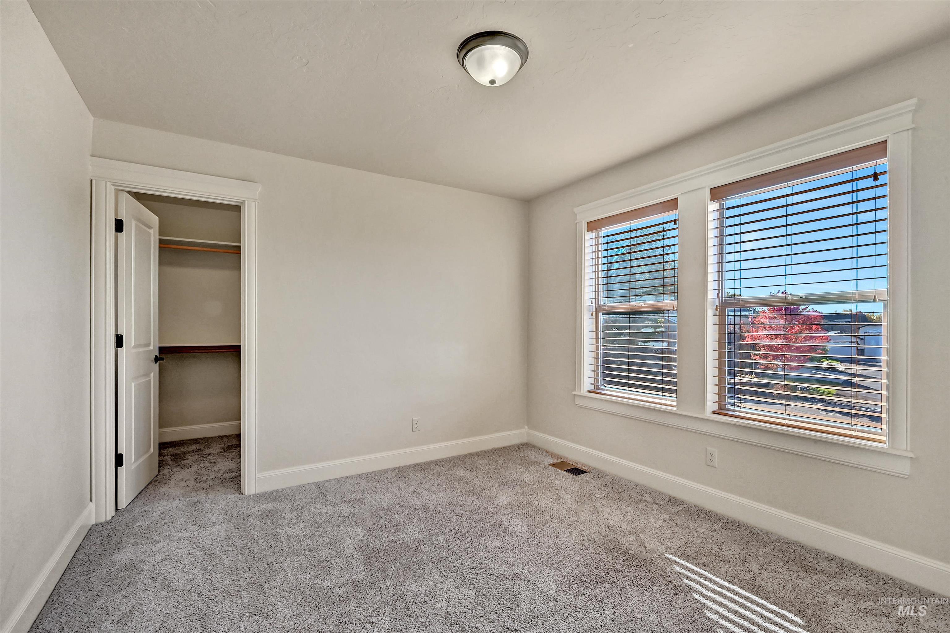 Unfurnished bedroom featuring light colored carpet and a walk in closet