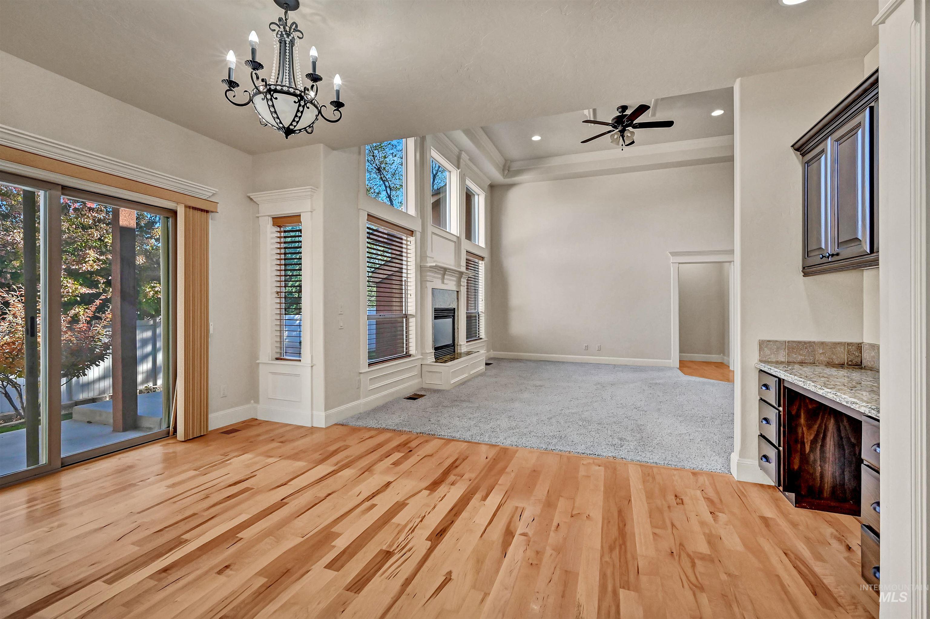 Unfurnished living room with light wood finished floors, a glass covered fireplace, ceiling fan, recessed lighting, and a chandelier