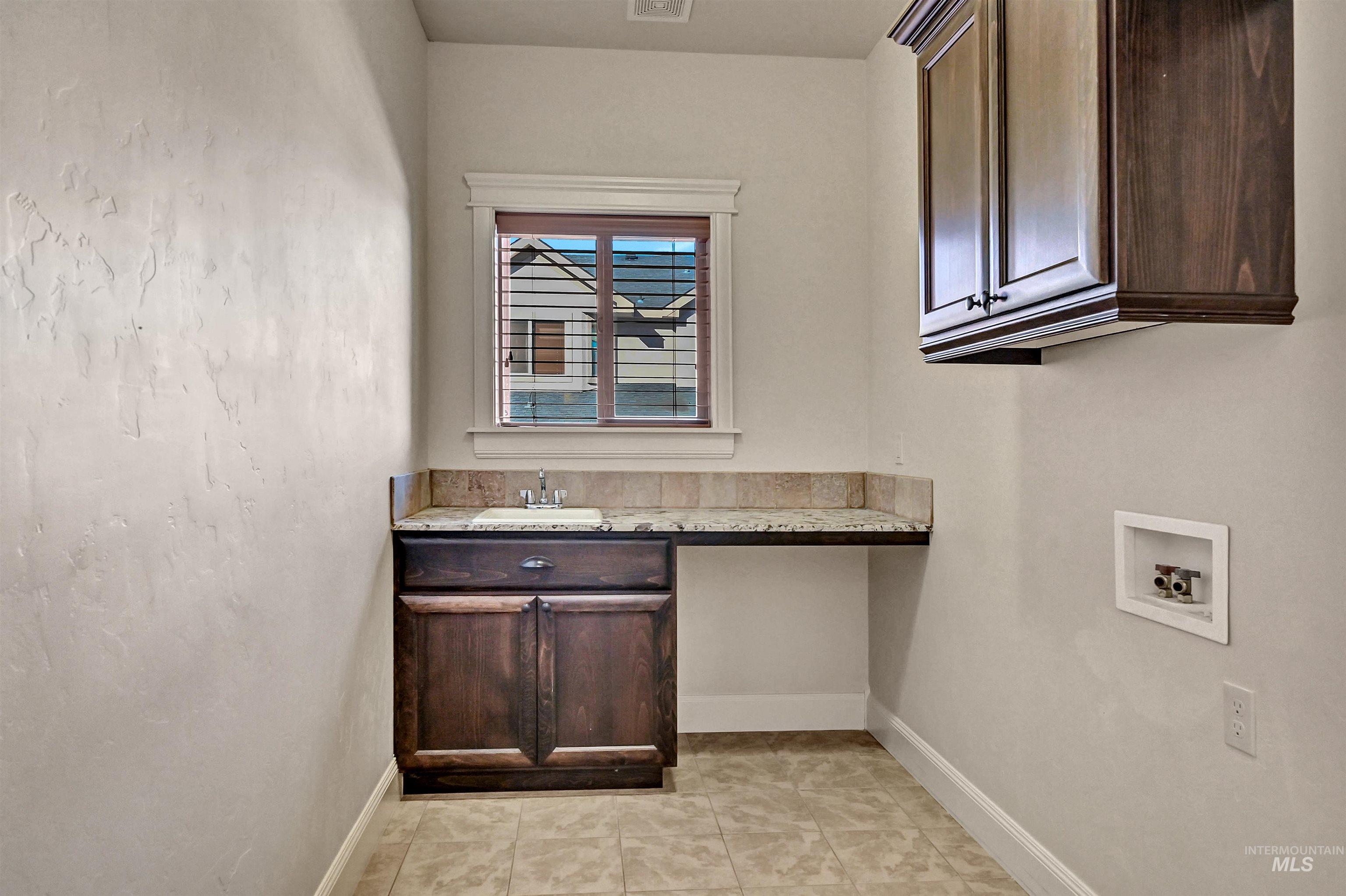 Laundry room with light tile patterned flooring, hookup for a washing machine, and cabinet space