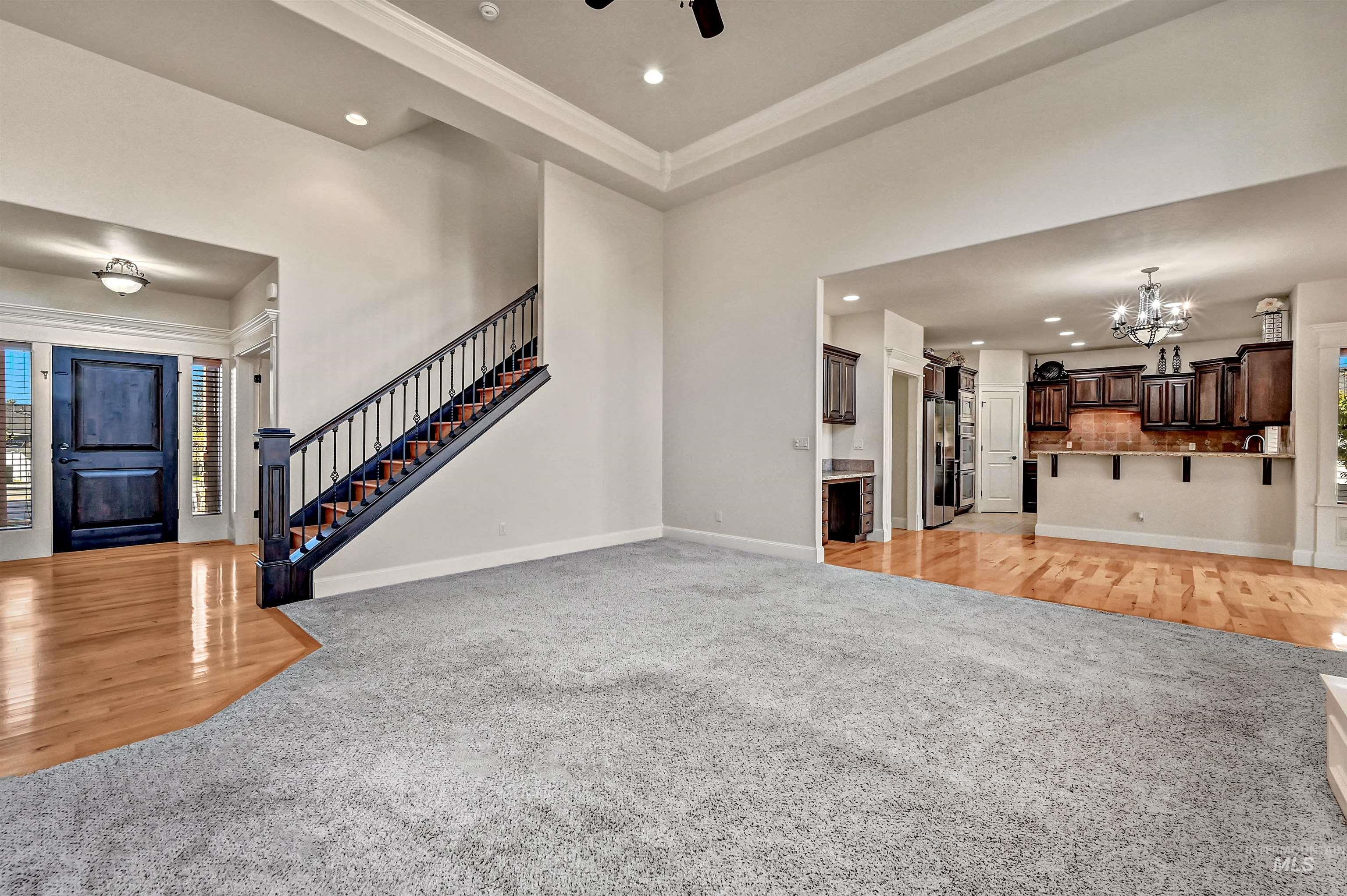 Unfurnished living room with light colored carpet, light wood-style flooring, recessed lighting, a chandelier, and stairway