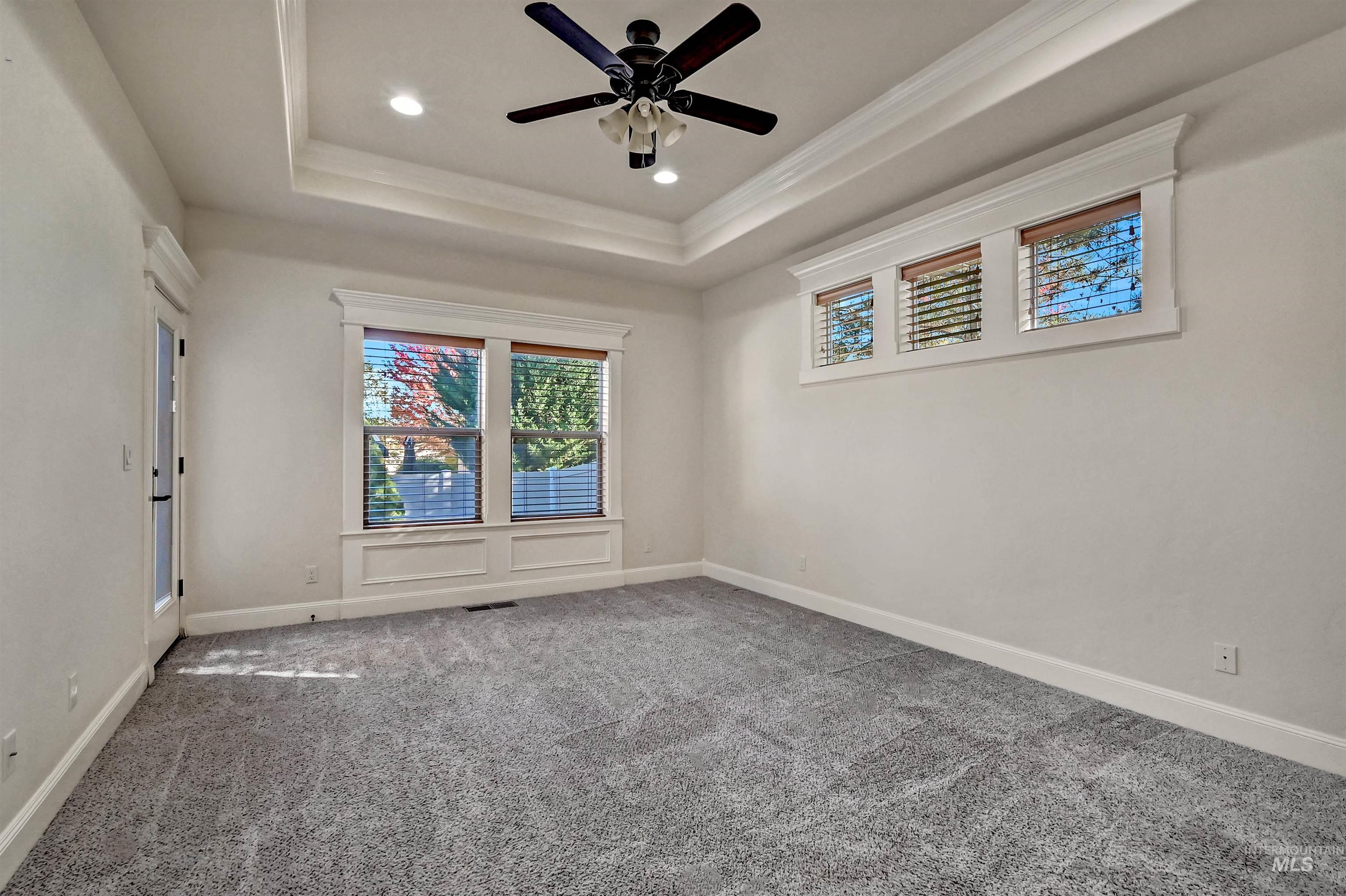 Unfurnished room featuring healthy amount of natural light, recessed lighting, carpet flooring, a tray ceiling, and ceiling fan