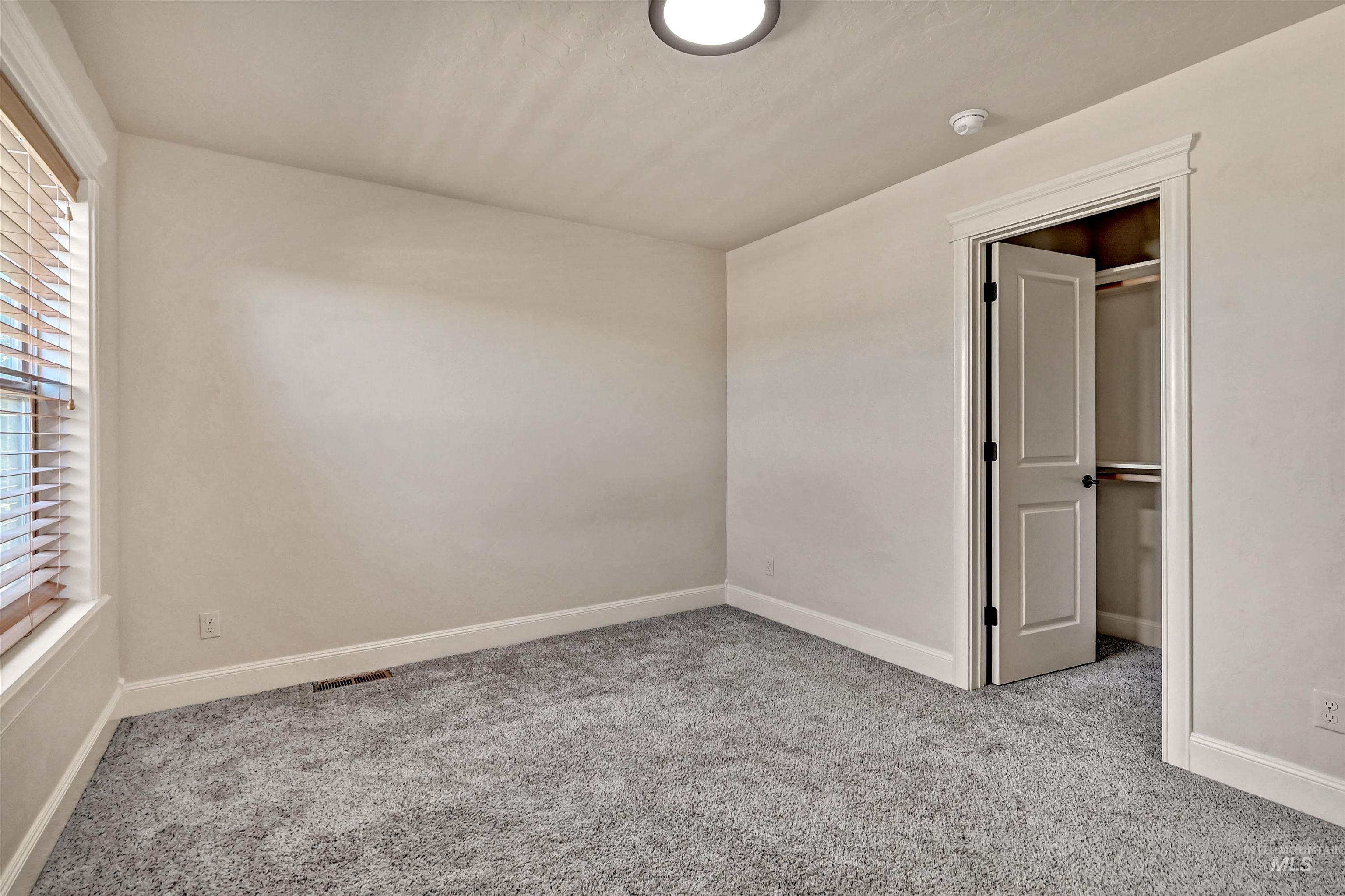 Unfurnished bedroom with light colored carpet and baseboards
