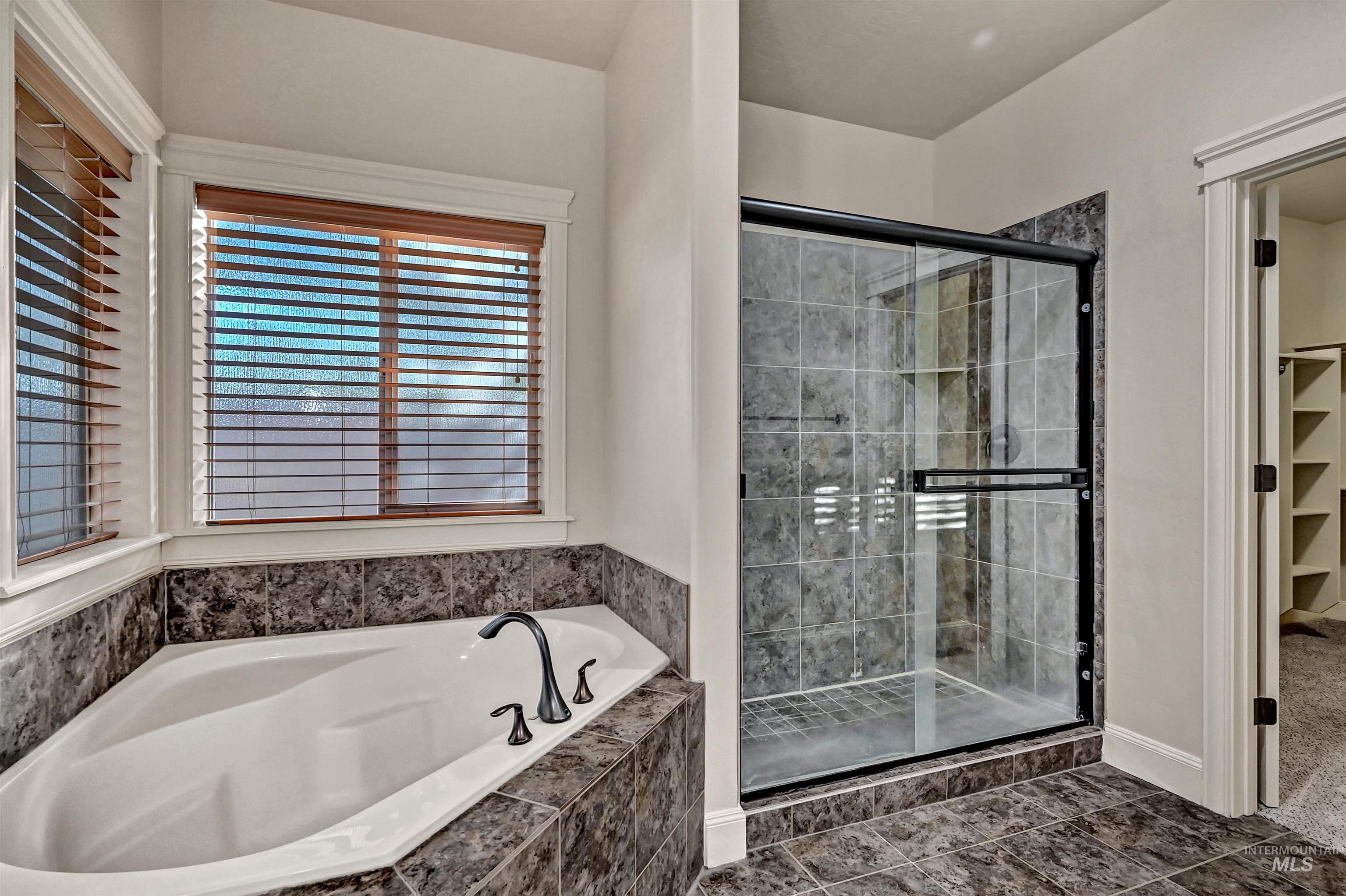 Full bathroom featuring a bath, a stall shower, and a walk in closet