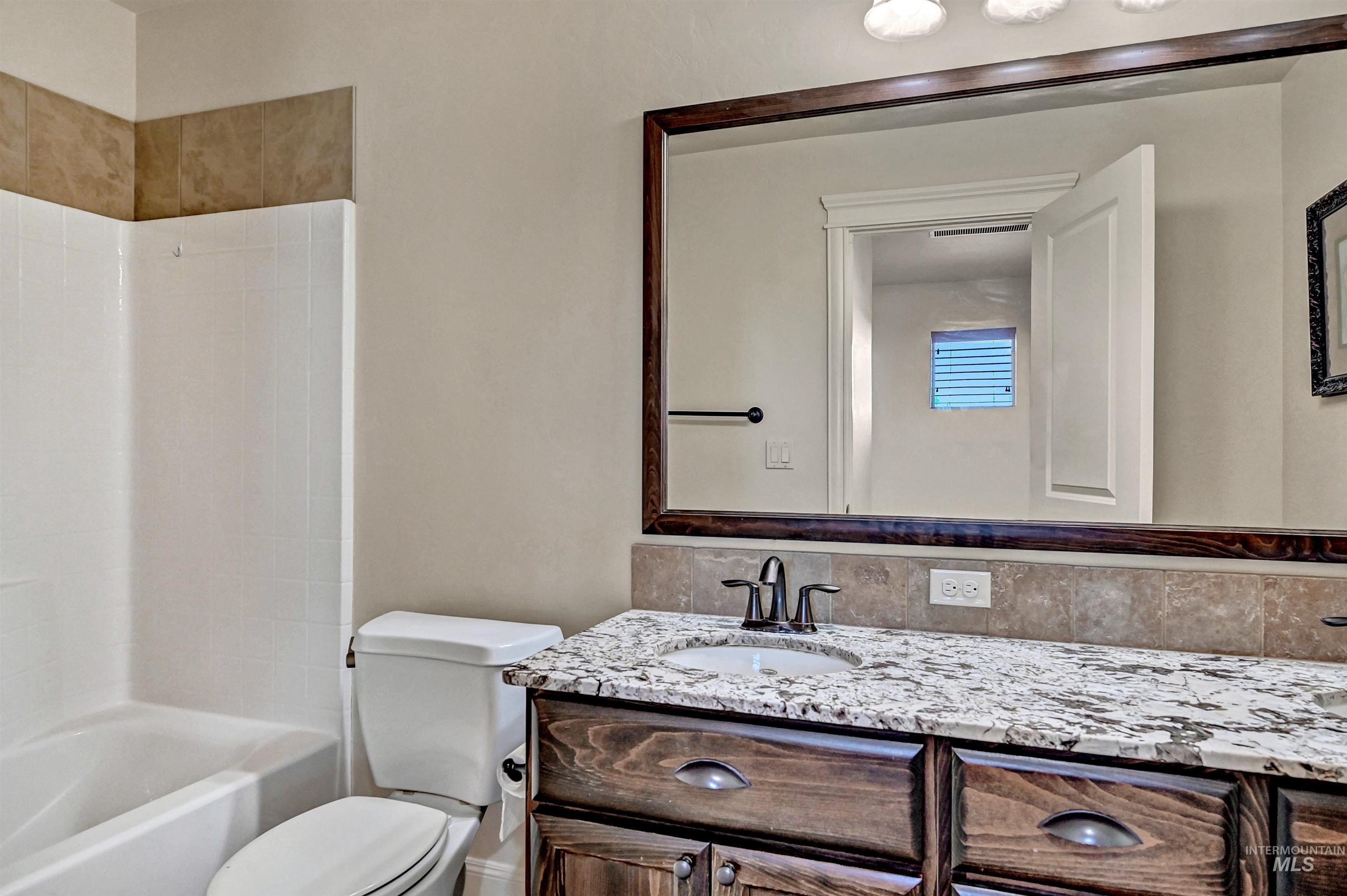 Full bath featuring vanity, shower / bathtub combination, and tasteful backsplash