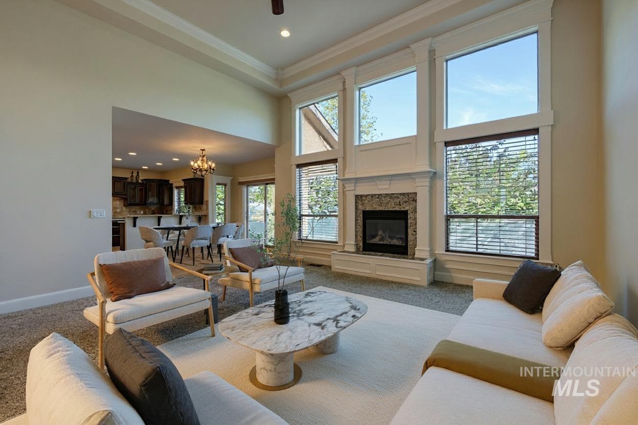 Carpeted living area with a chandelier, a towering ceiling, a premium fireplace, recessed lighting, and a ceiling fan