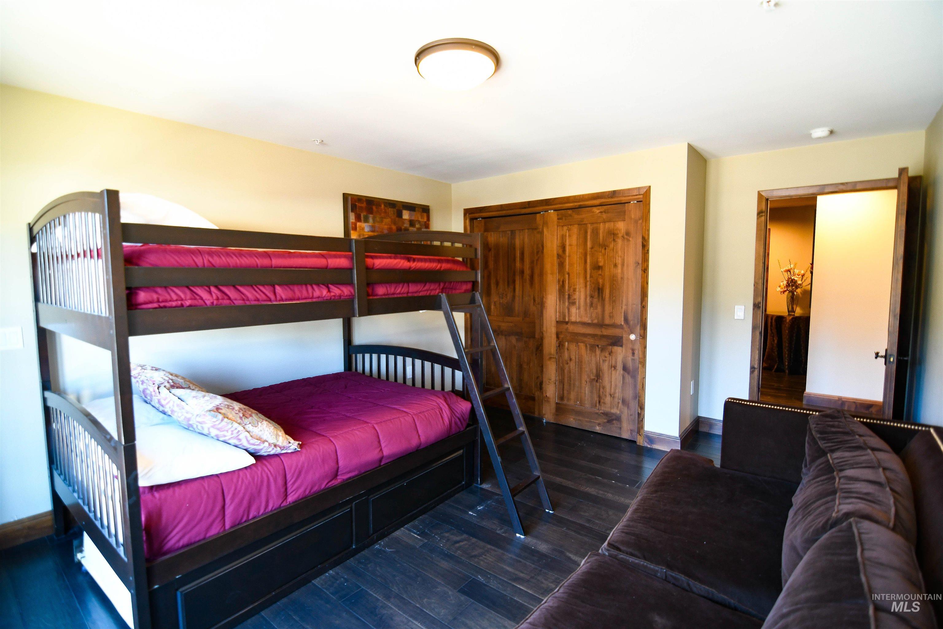 Bedroom with dark wood finished floors and a closet