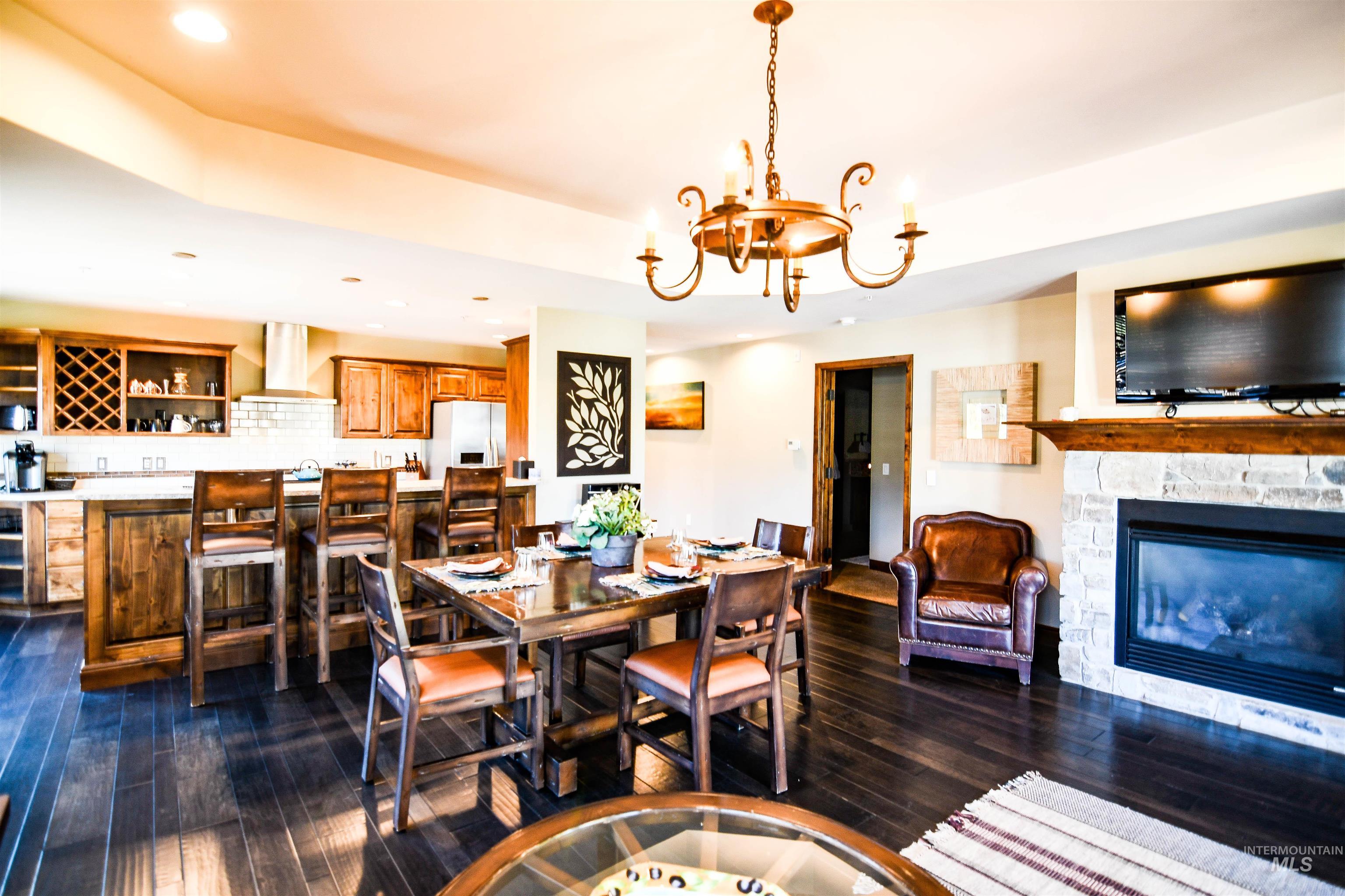 Dining room featuring dark wood finished floors, recessed lighting, a fireplace, a chandelier, and a tray ceiling