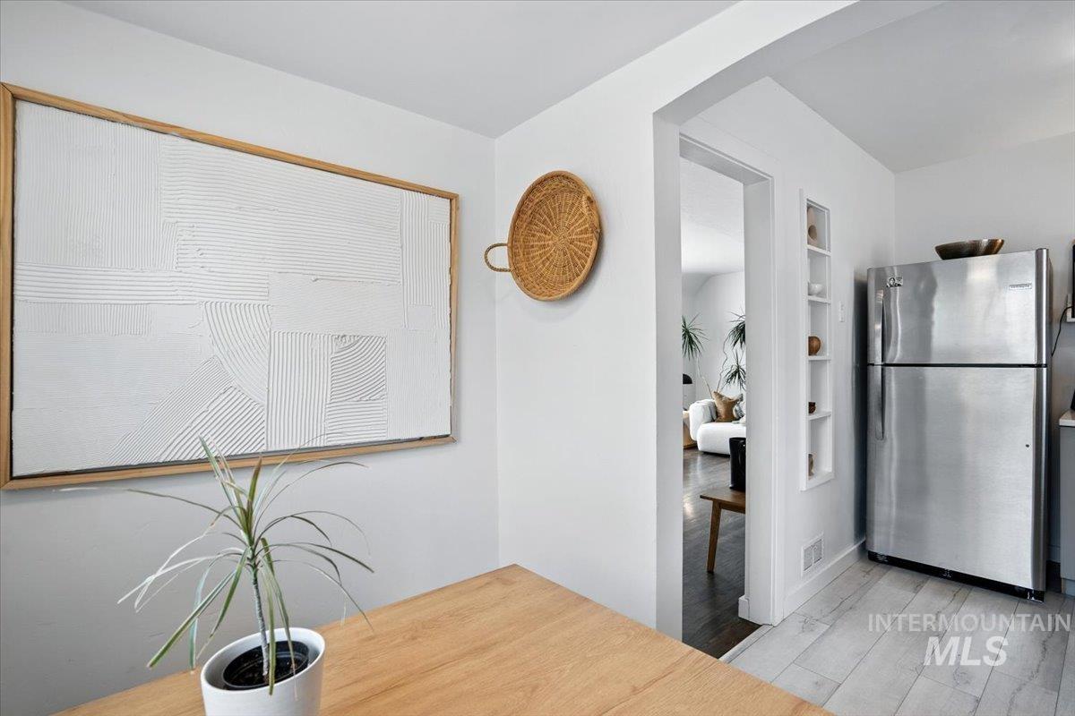 Unfurnished dining area featuring light wood-style floors, built in shelves, and arched walkways