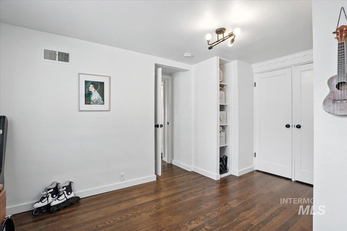 Unfurnished bedroom with dark wood-style floors and a closet