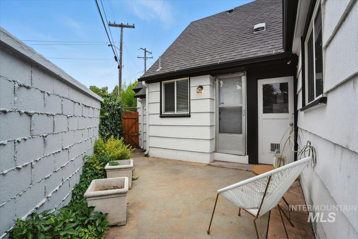 Rear view of house featuring roof with shingles and a patio area