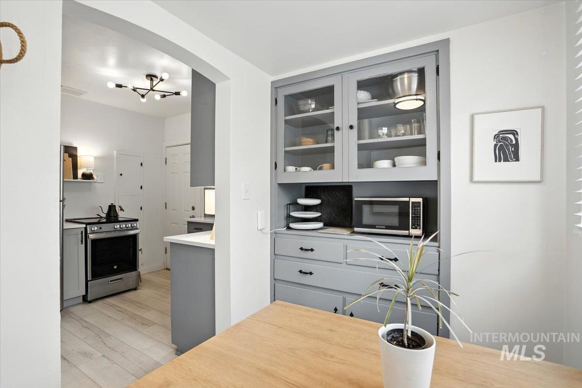 Kitchen featuring gray cabinetry, glass insert cabinets, stainless steel appliances, light countertops, and light wood-type flooring