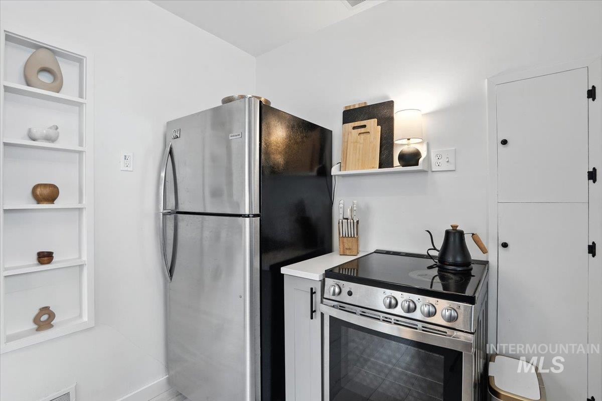 Kitchen with stainless steel appliances, light countertops, and open shelves