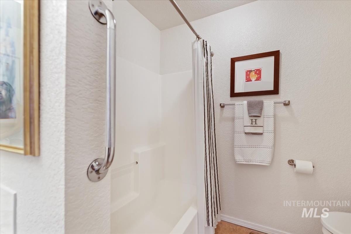 Full bath featuring curtained shower and a textured wall