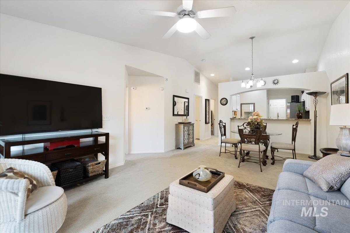 Carpeted living room with a chandelier, lofted ceiling, ceiling fan, recessed lighting, and arched walkways