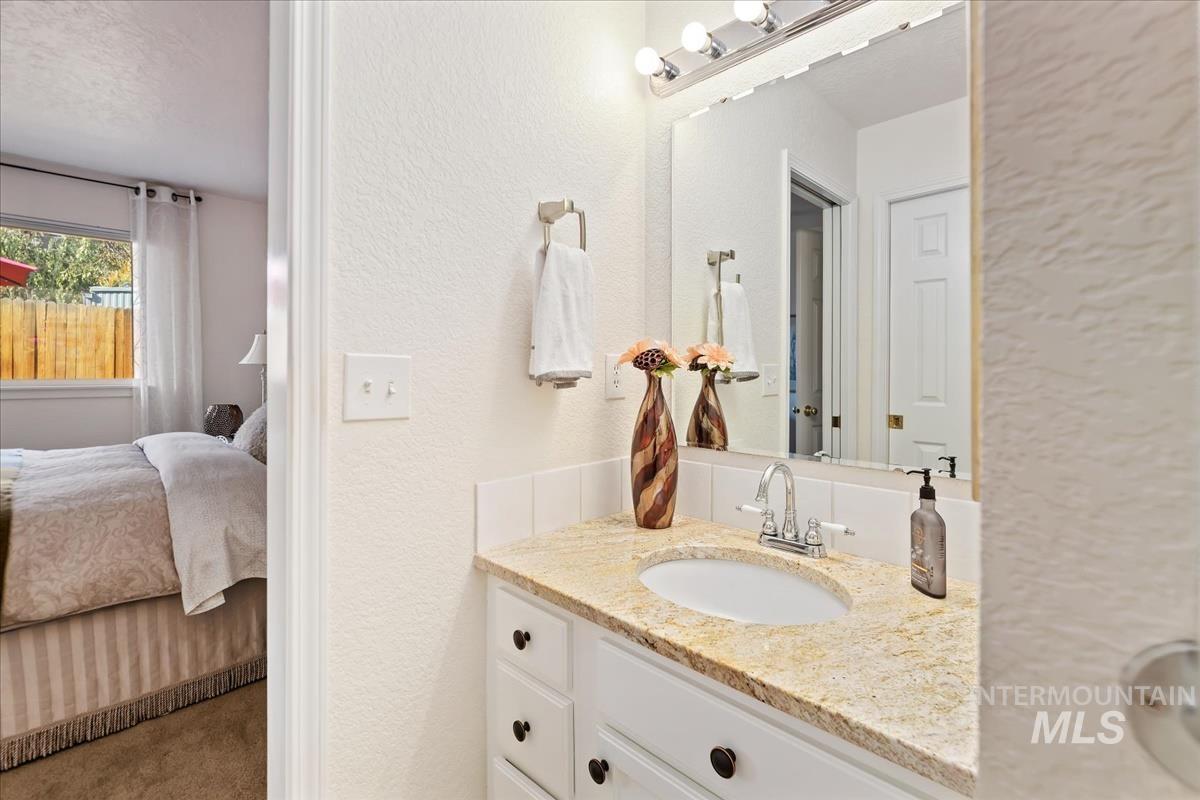 Ensuite bathroom with a textured wall, vanity, and carpet floors