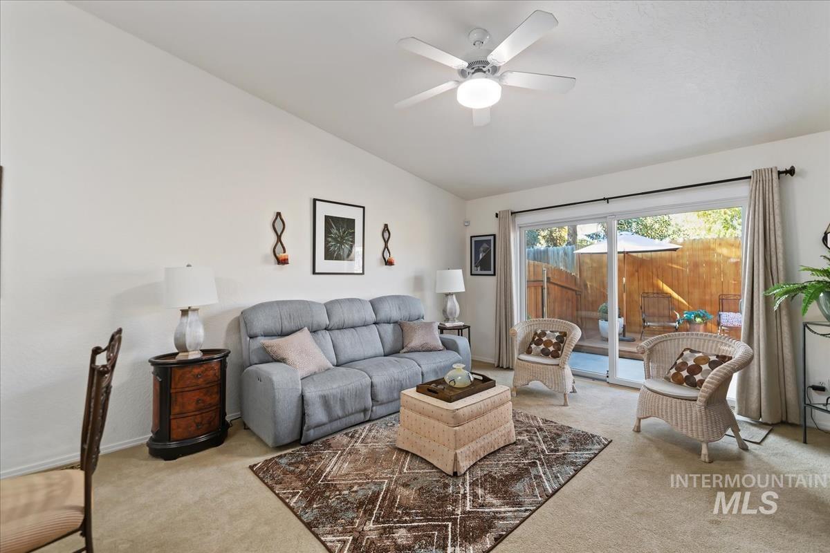 Living area with lofted ceiling, light carpet, and ceiling fan