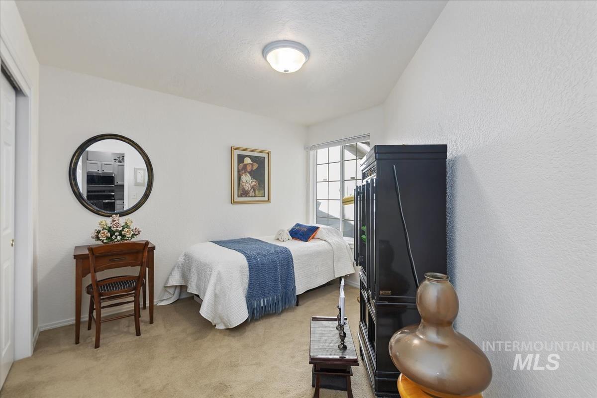 Bedroom featuring light colored carpet, a closet, a textured wall, and a textured ceiling