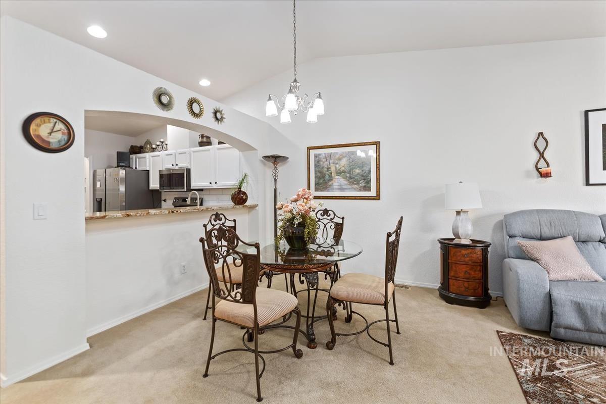 Dining room with vaulted ceiling, a chandelier, light carpet, recessed lighting, and arched walkways