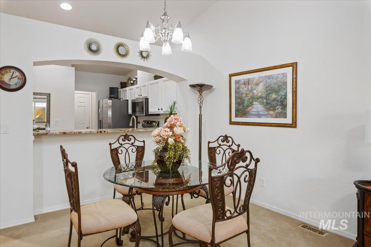Dining space with light colored carpet, arched walkways, and a chandelier