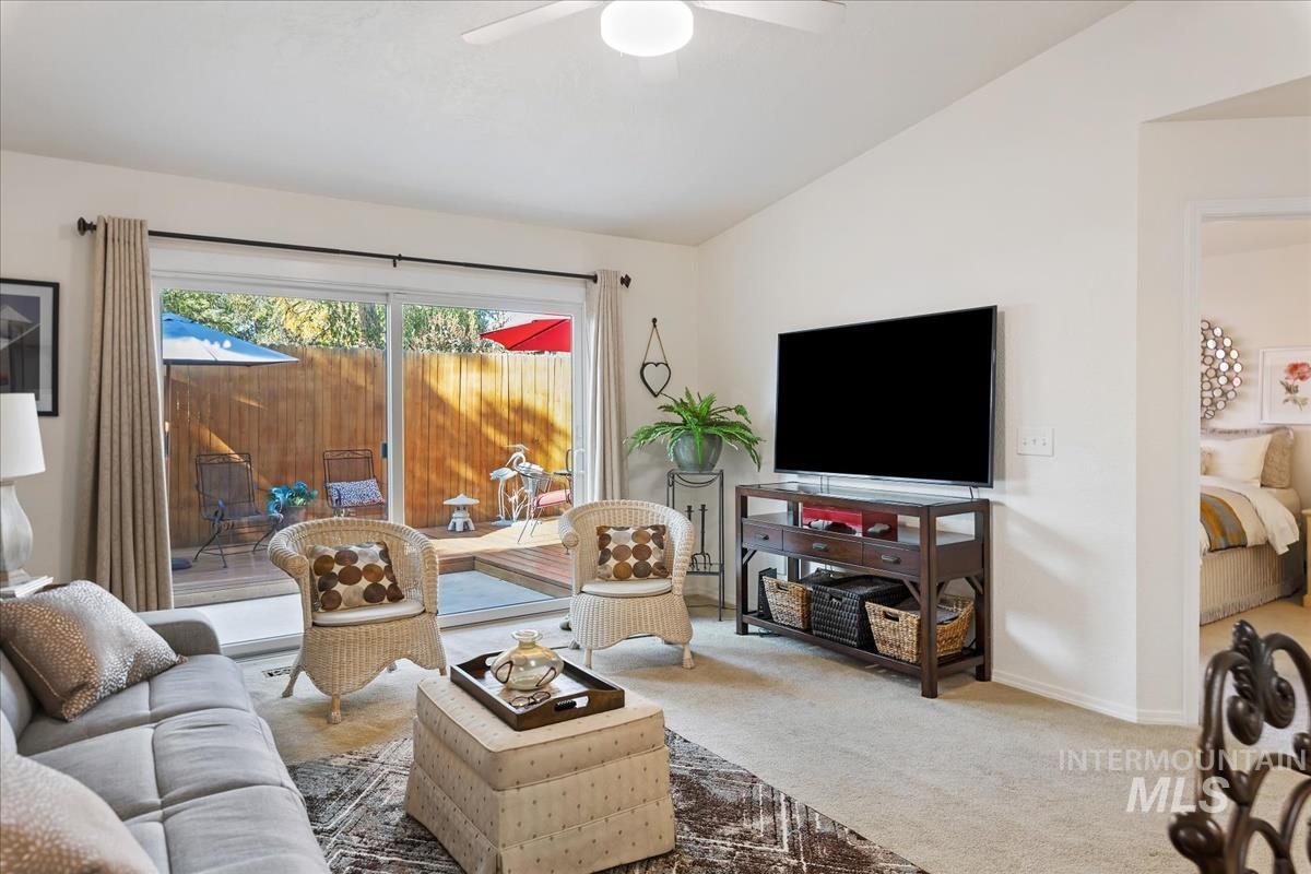 Carpeted living area featuring lofted ceiling and baseboards