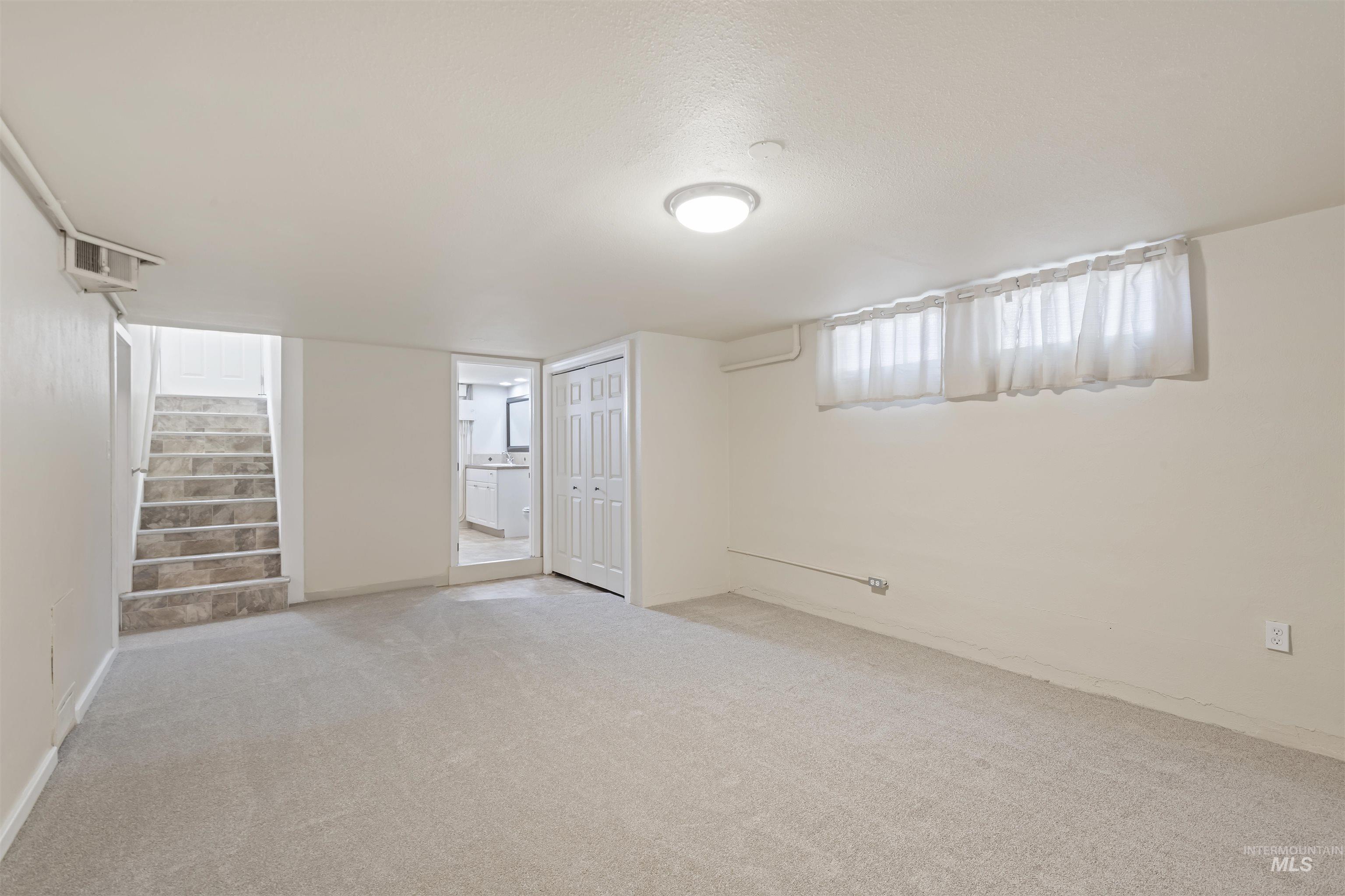 Basement featuring carpet floors, stairway, and a textured ceiling