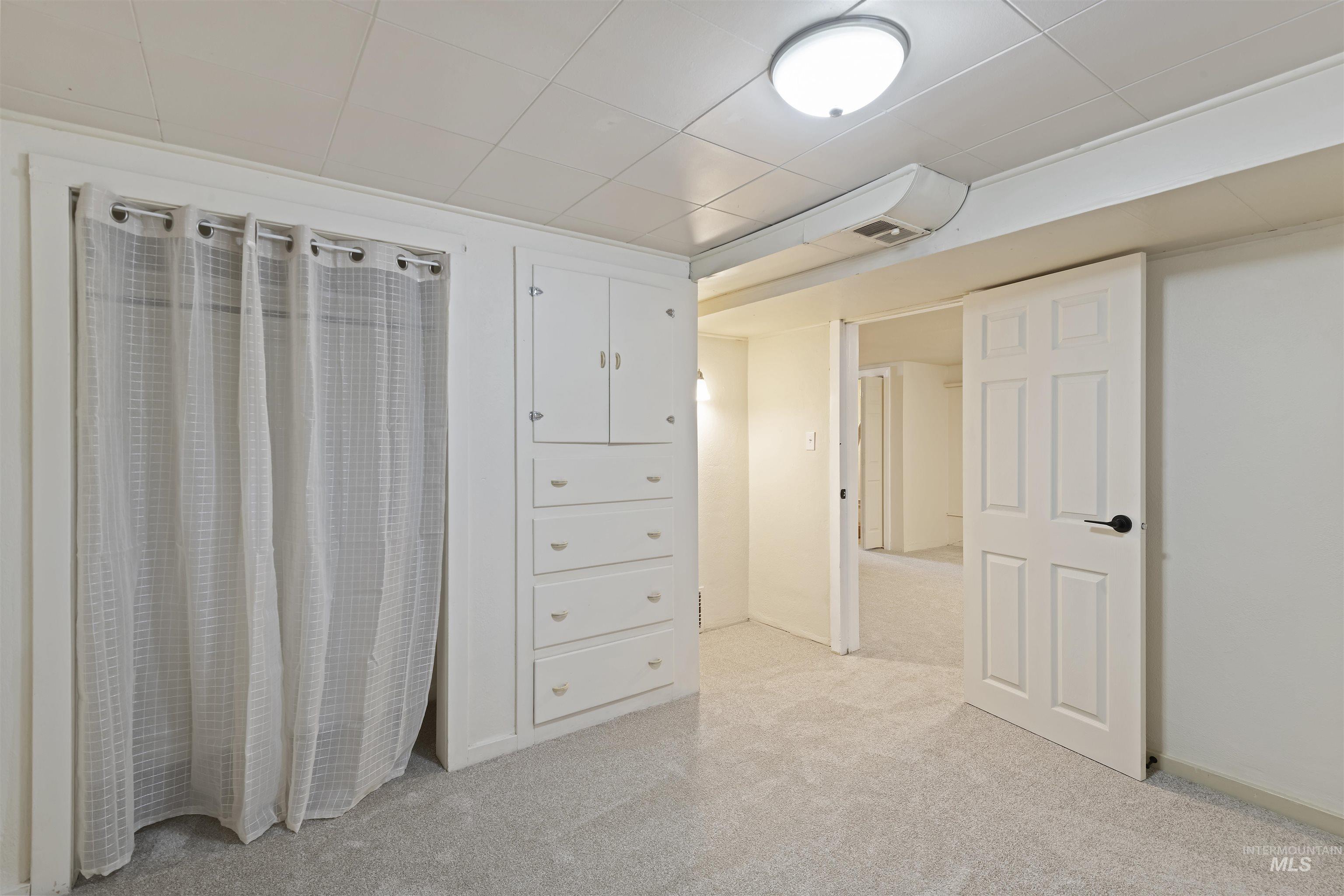 Interior space with light colored carpet and a drop ceiling