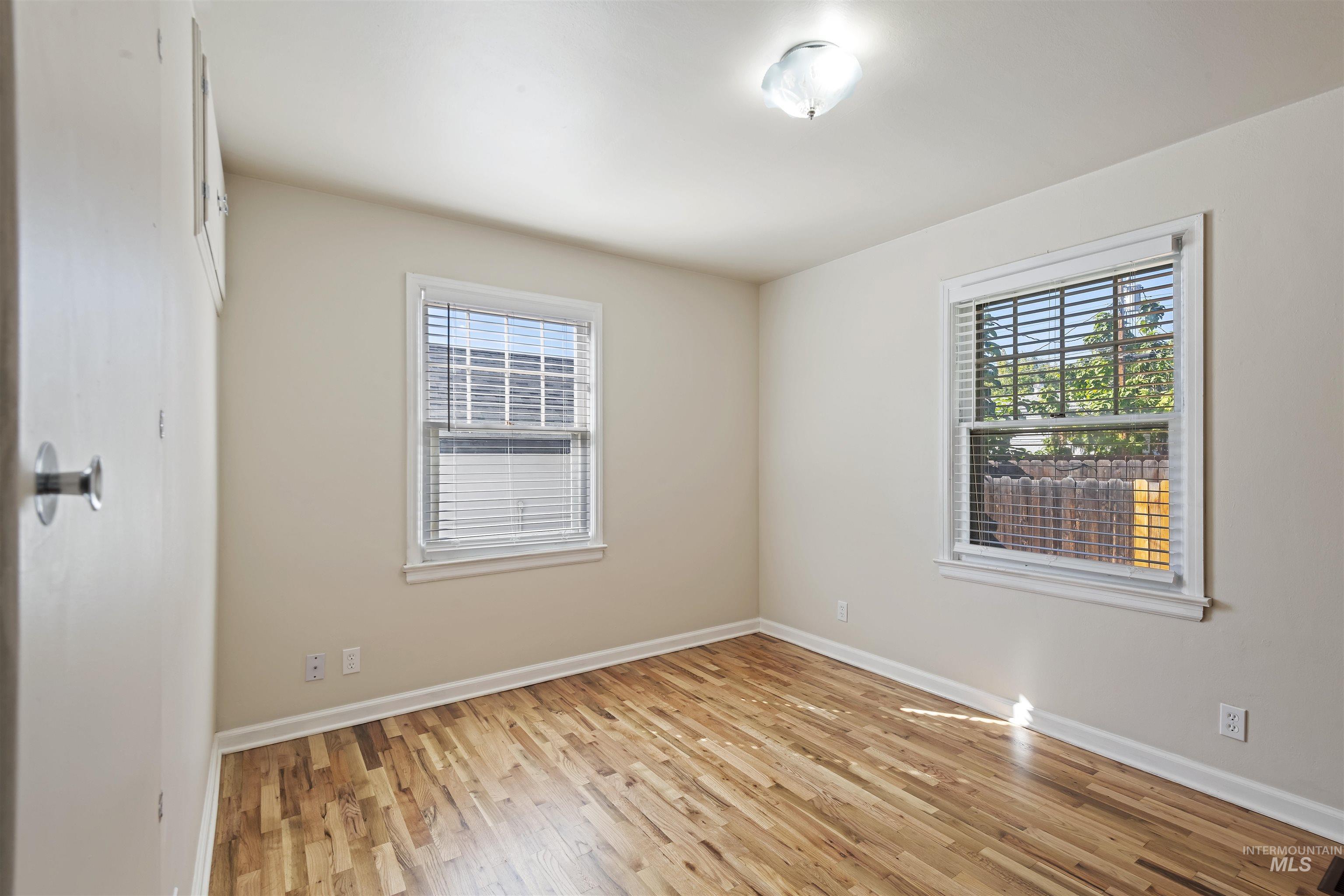Spare room featuring light wood-style flooring and baseboards