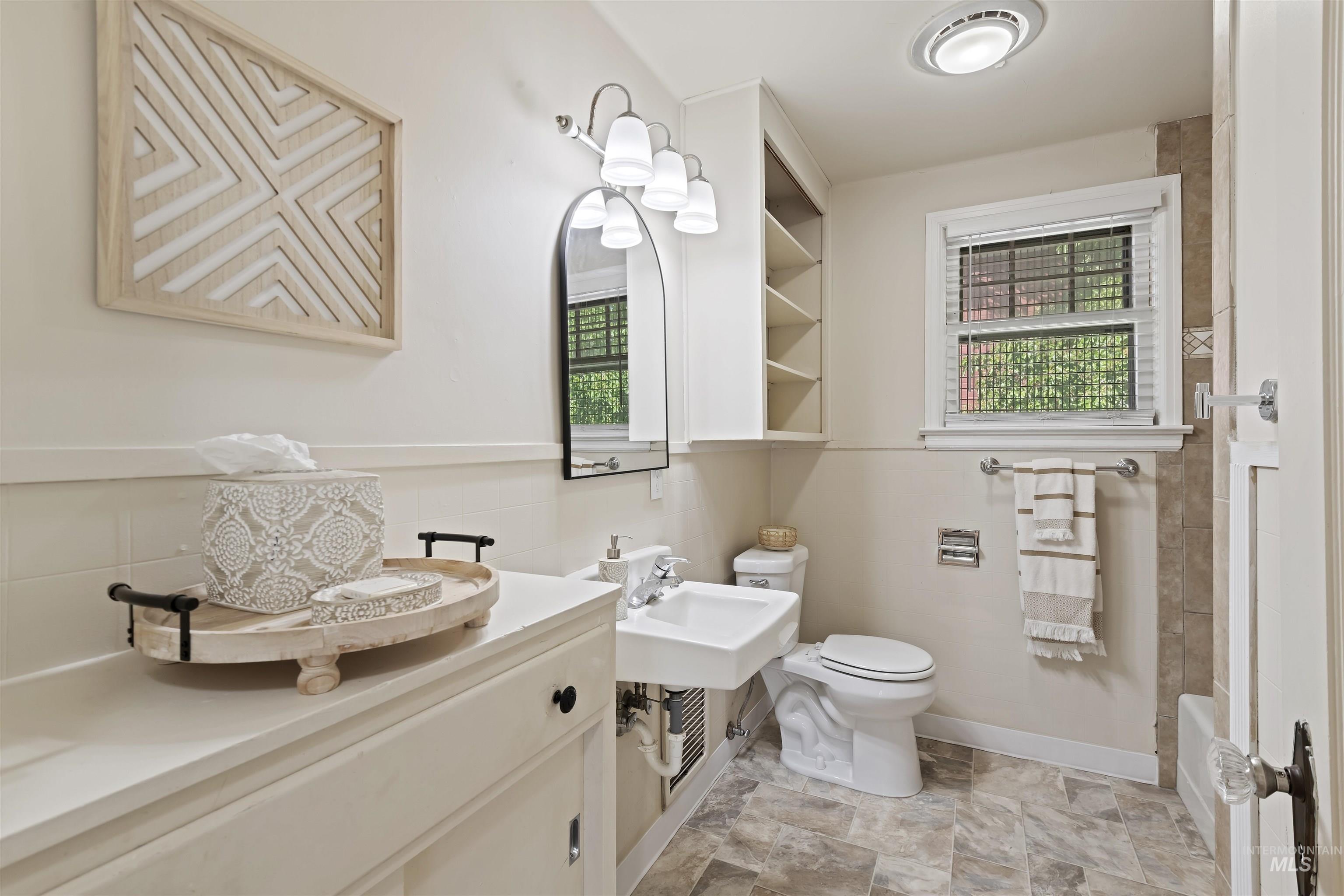 Bathroom featuring healthy amount of natural light, tasteful backsplash, shower / tub combination, and stone finish flooring