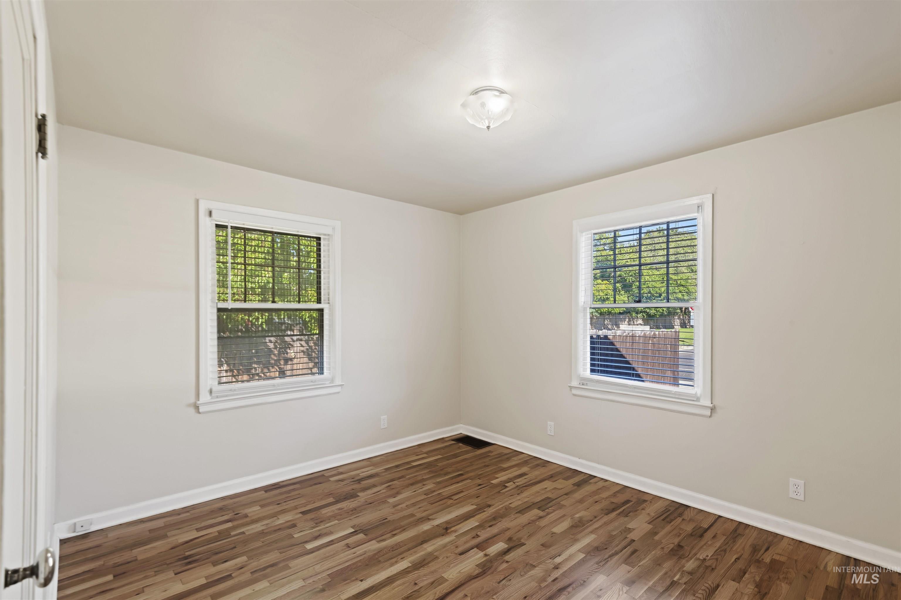 Unfurnished room featuring dark wood-style floors and healthy amount of natural light