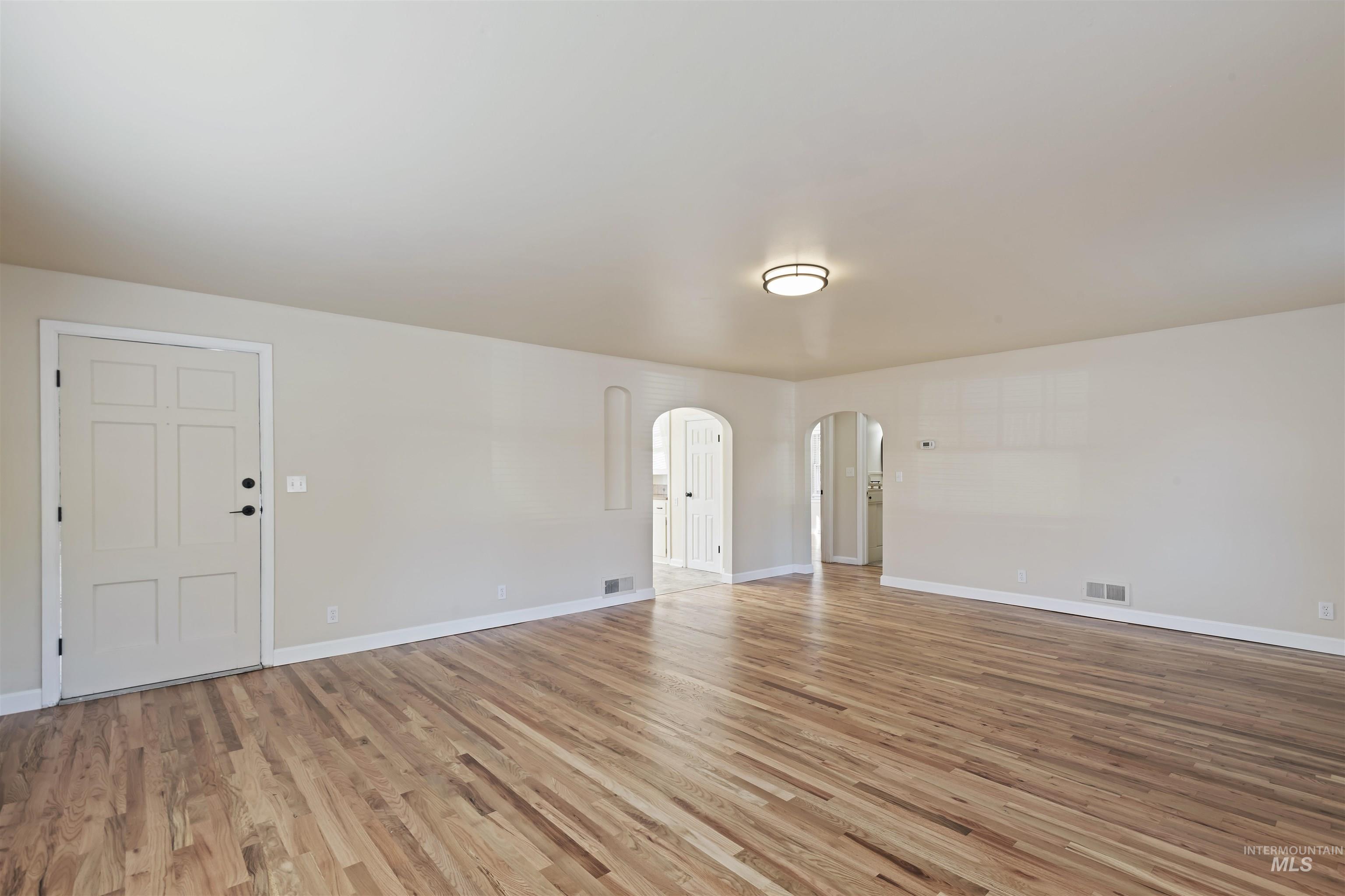 Unfurnished room with light wood-style floors and arched walkways