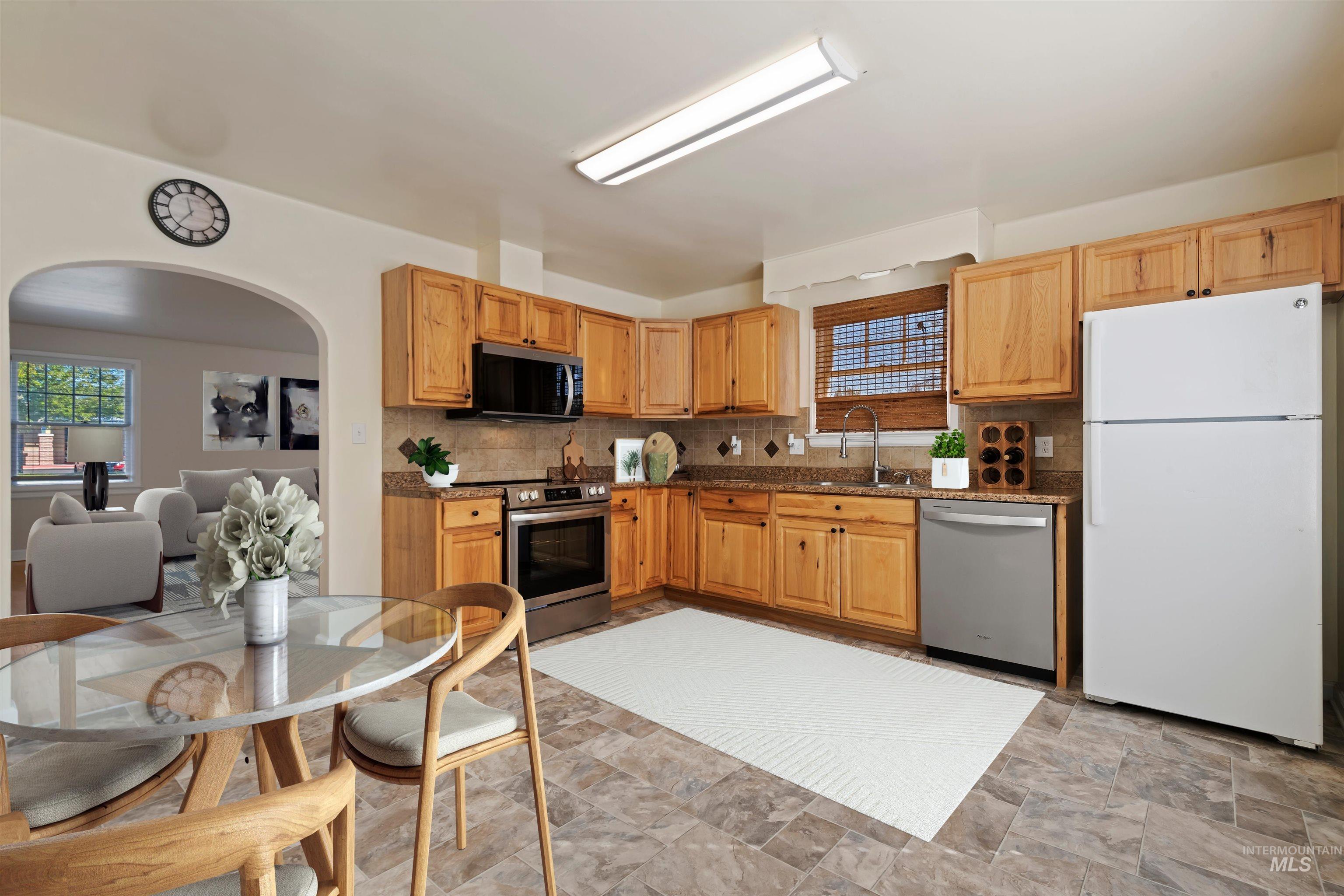 Kitchen featuring arched walkways, stainless steel appliances, backsplash, and healthy amount of natural light